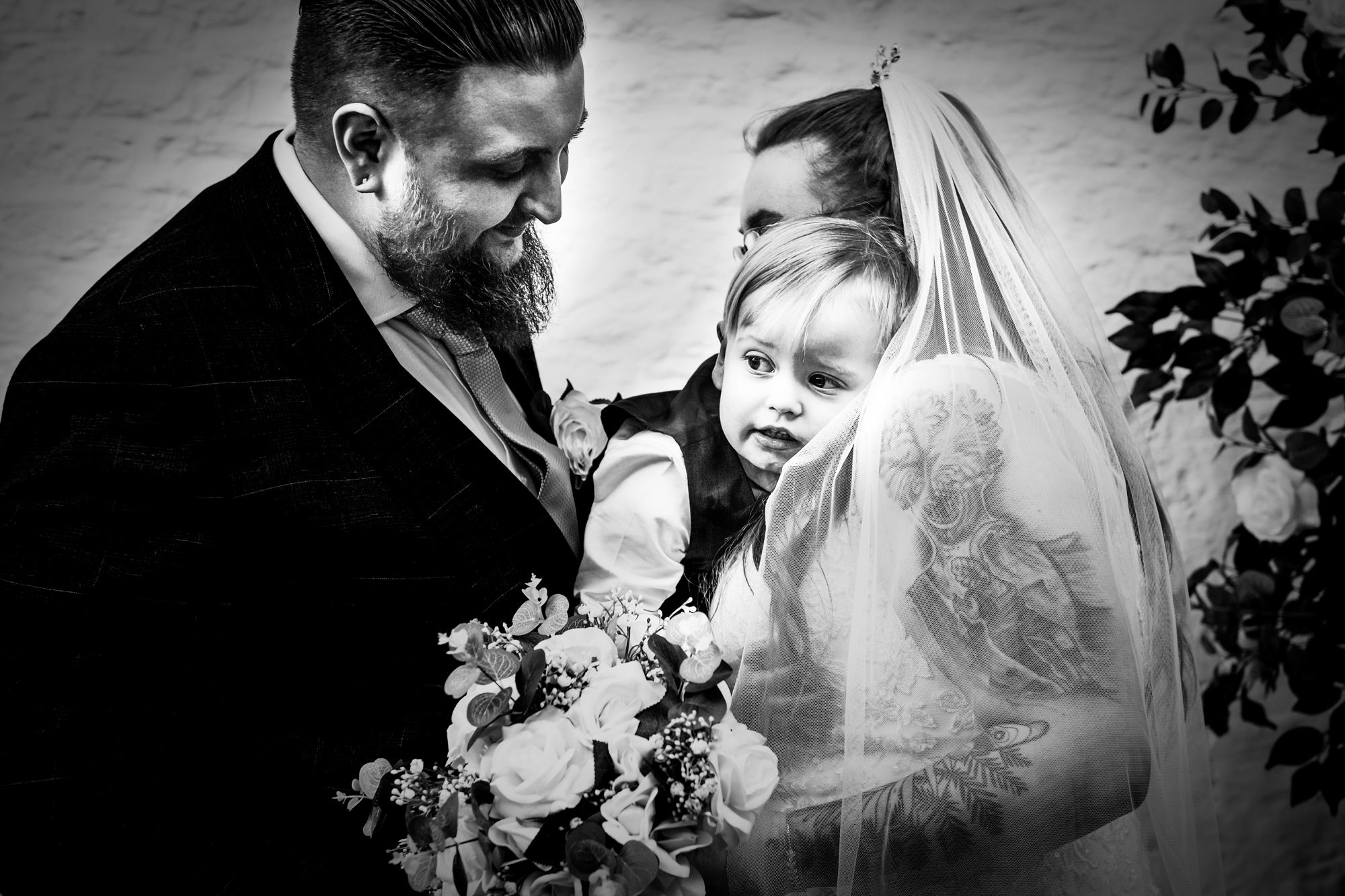 Nat and Jon cuddle Theo close as he looks away from the camera.