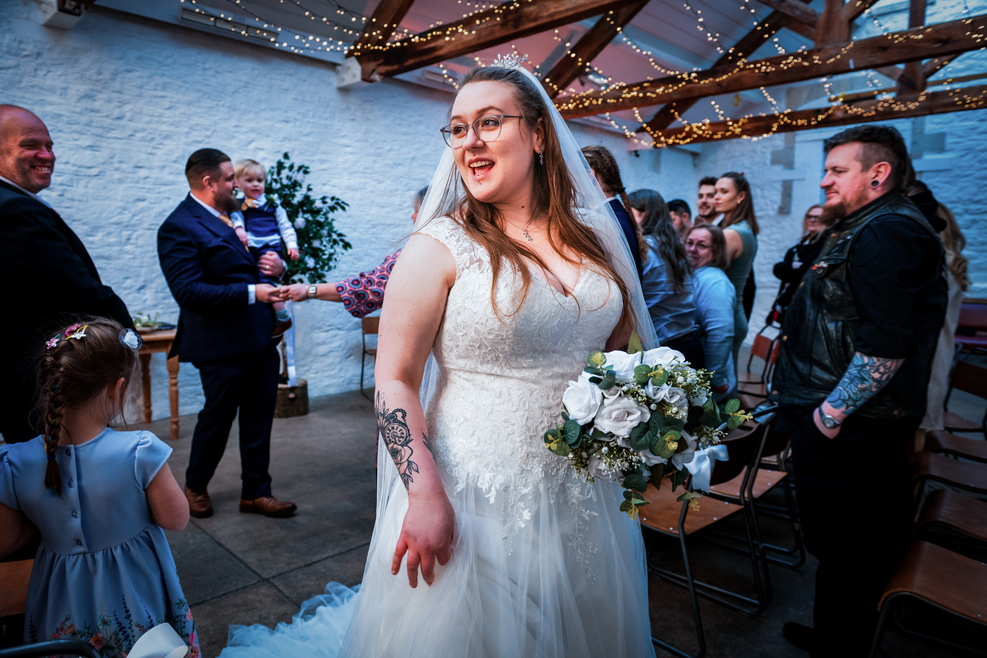 Nat turns with her bouquet after the ceremony while guests mingle inside Silk Mill Studios.
