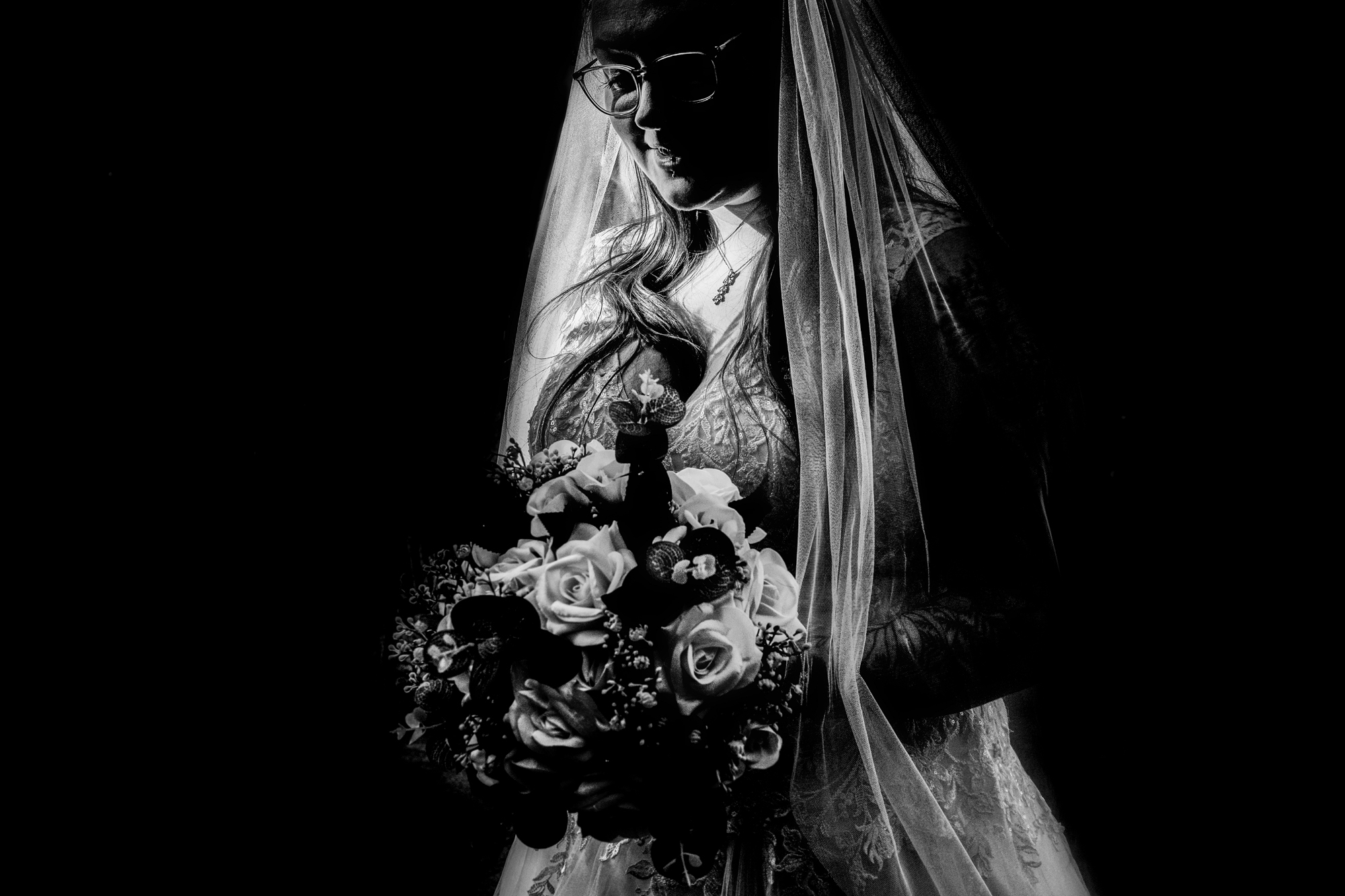 Nat stands with her bouquet in dramatic light and shadow after the ceremony.