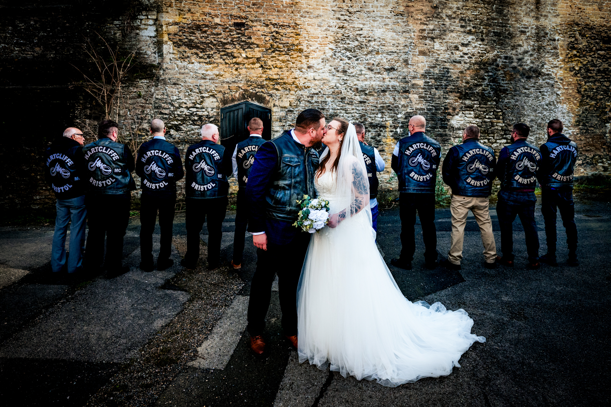 Nat and Jon kiss in front of Hartcliffe MC Bristol members lined up behind them.