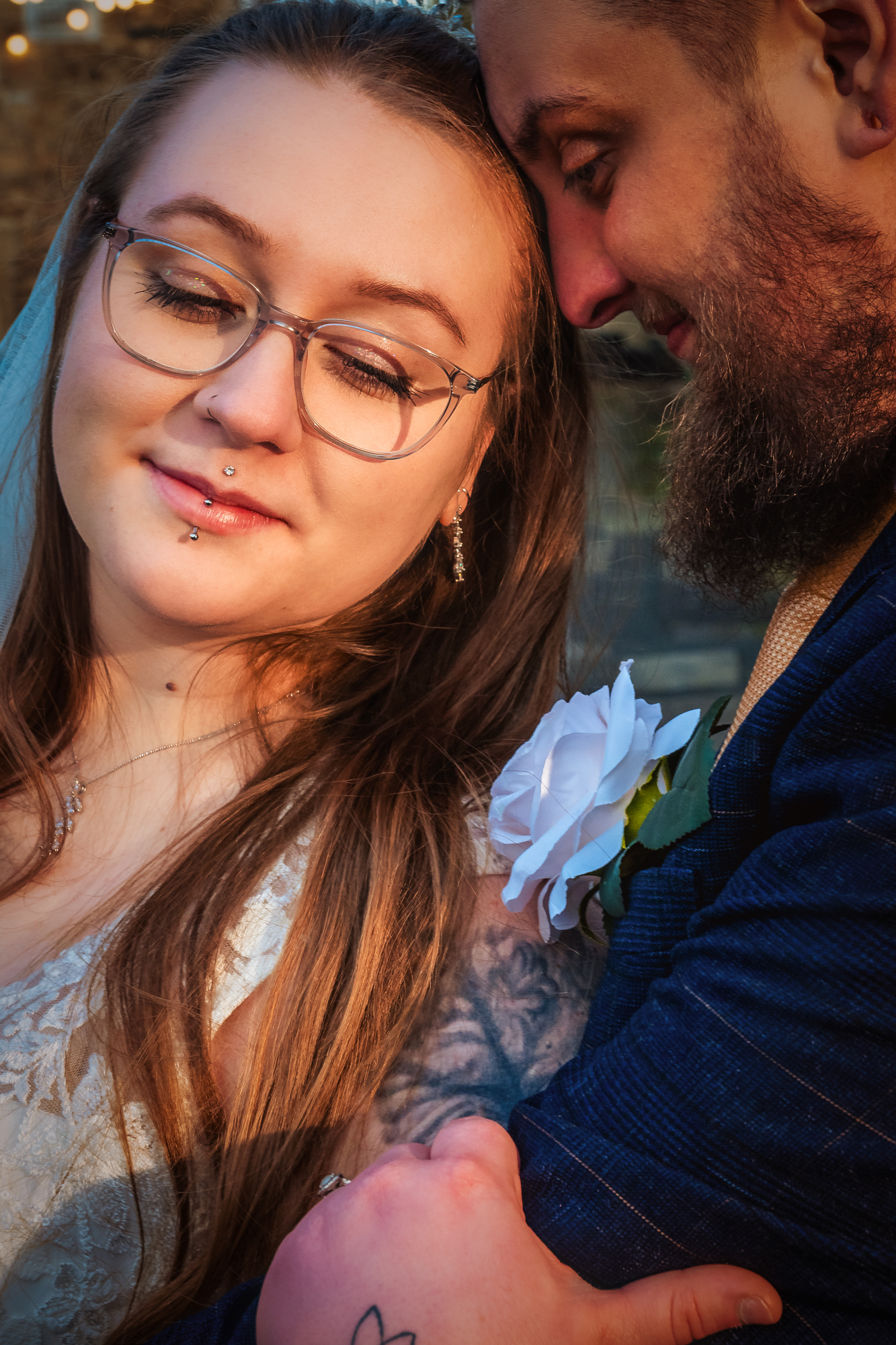 Close-up portrait of Nat with looking down as Jon leans in beside her.