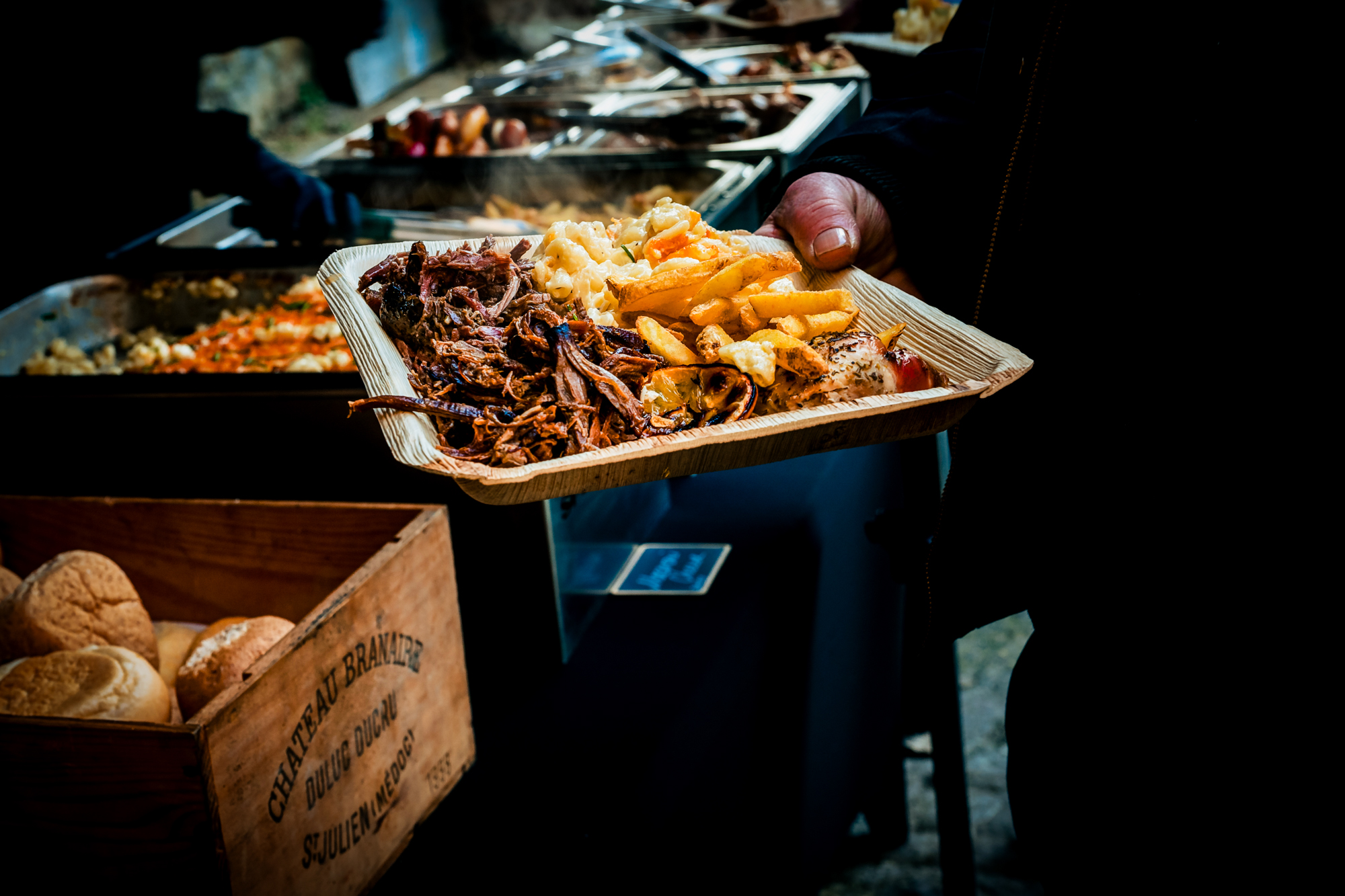 Guest carries a plate of wedding food beside the outdoor buffet at Silk Mill Studios.