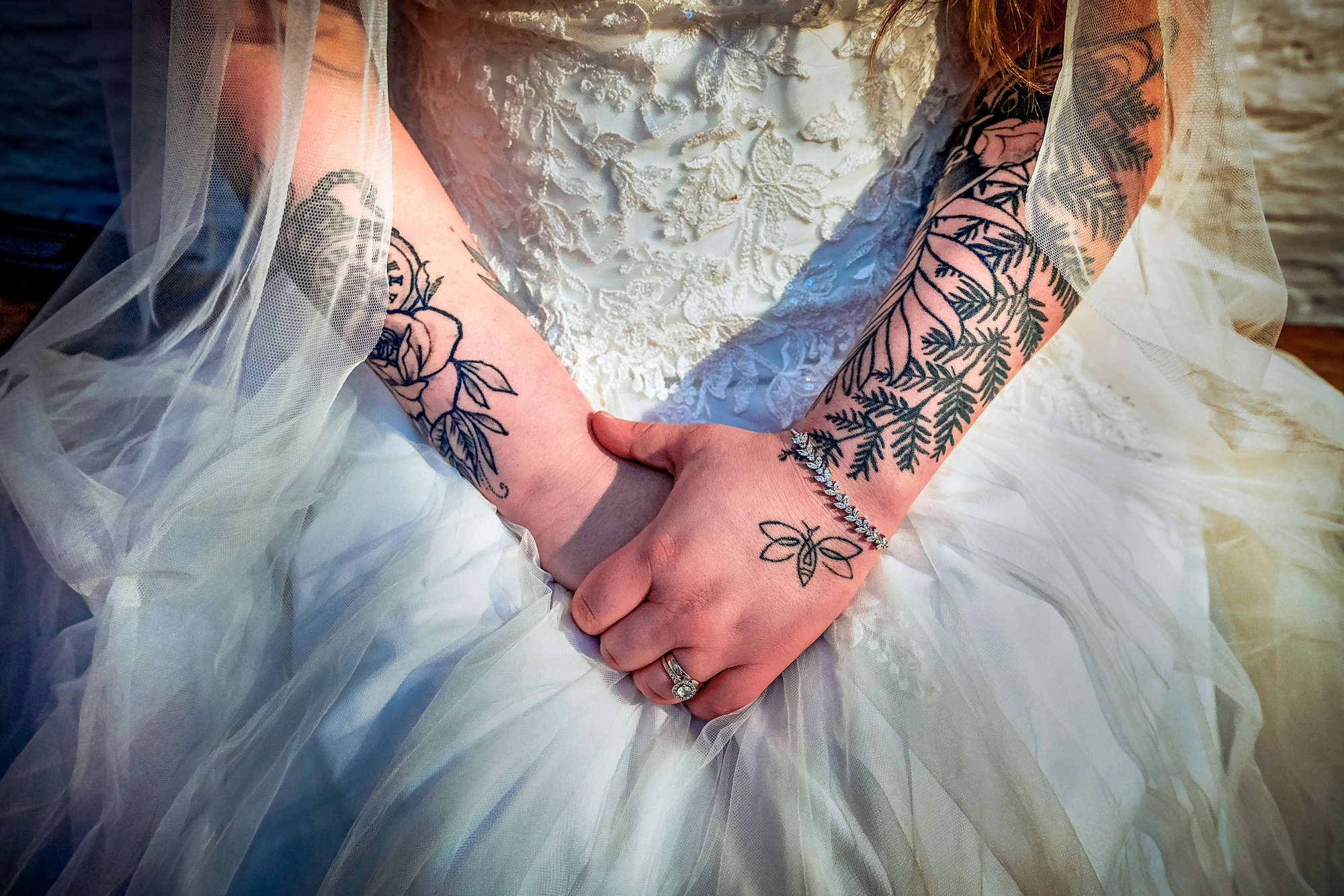 Close-up of Nat’s tattooed hands resting against her wedding dress after the ceremony.