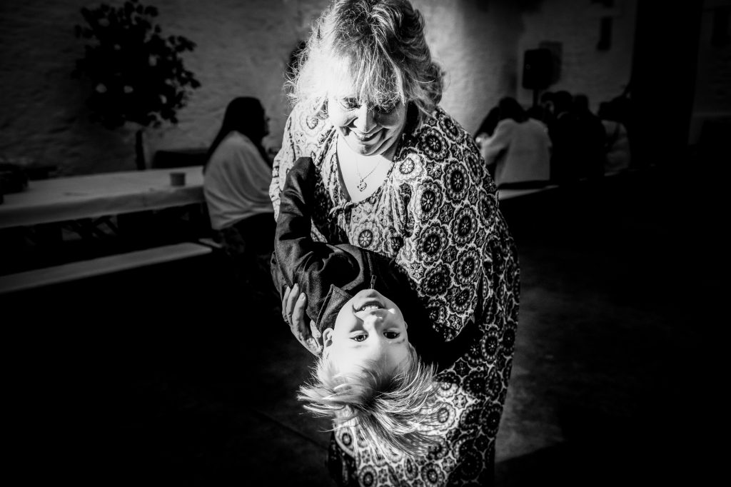Grandmother swings a smiling little boy upside down during the wedding evening party.