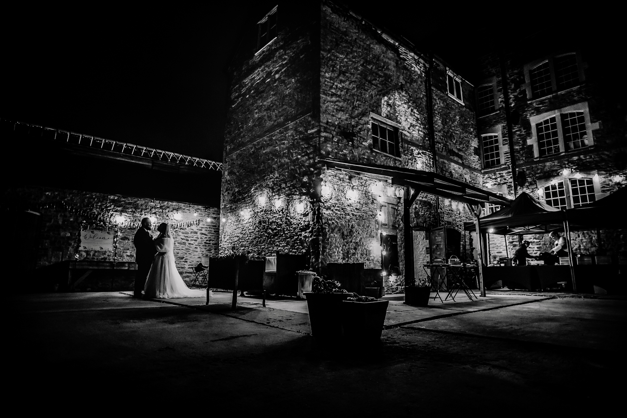 Wide night view of Silk Mill Studios courtyard with Nat and Jon standing together outside.