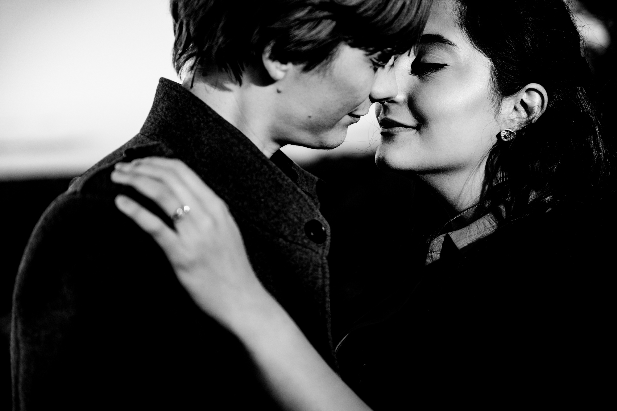 Black and white close-up of couple smiling nose to nose during intimate portrait.