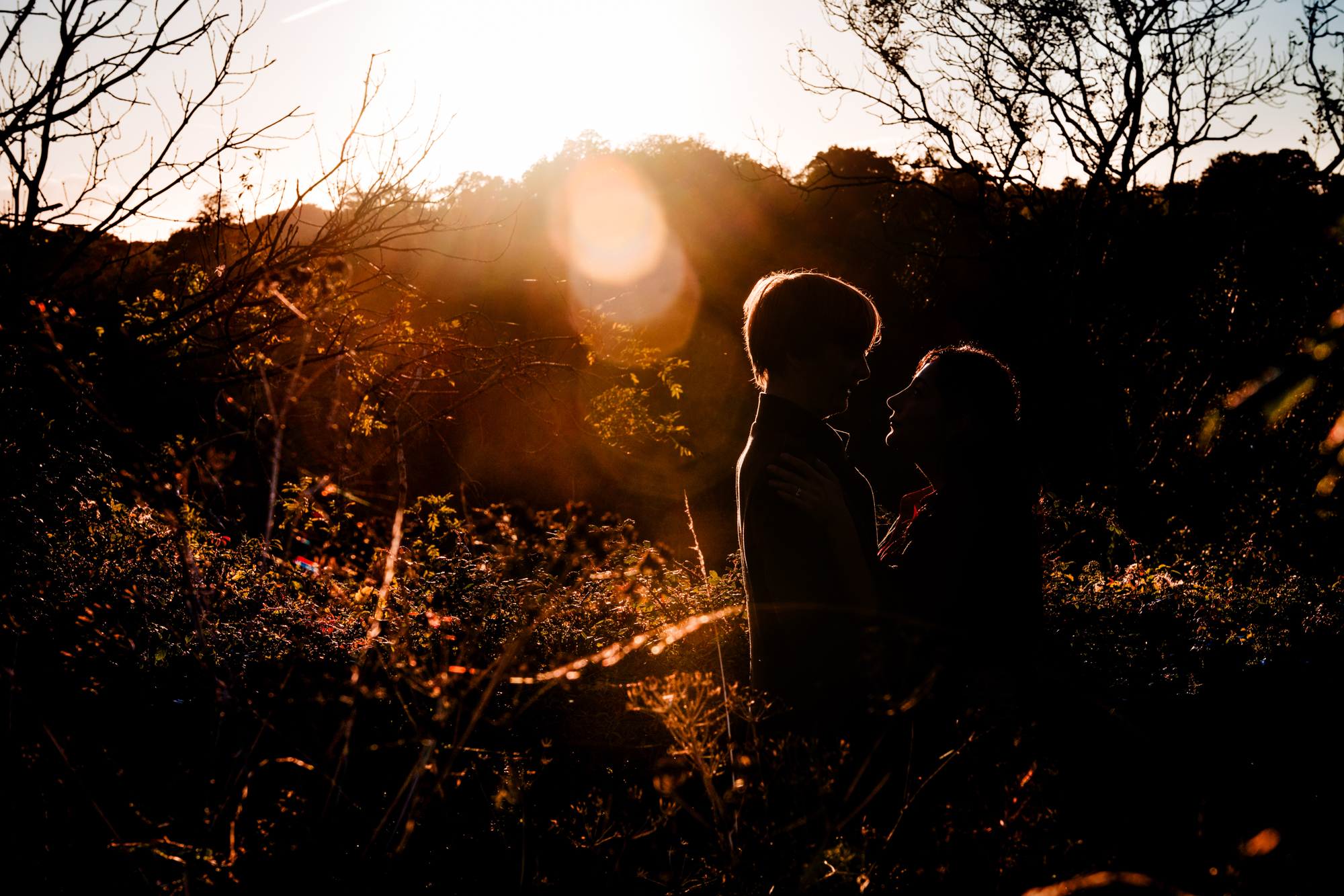 Silhouetted couple holding each other in warm sunset light during Clifton engagement shoot.