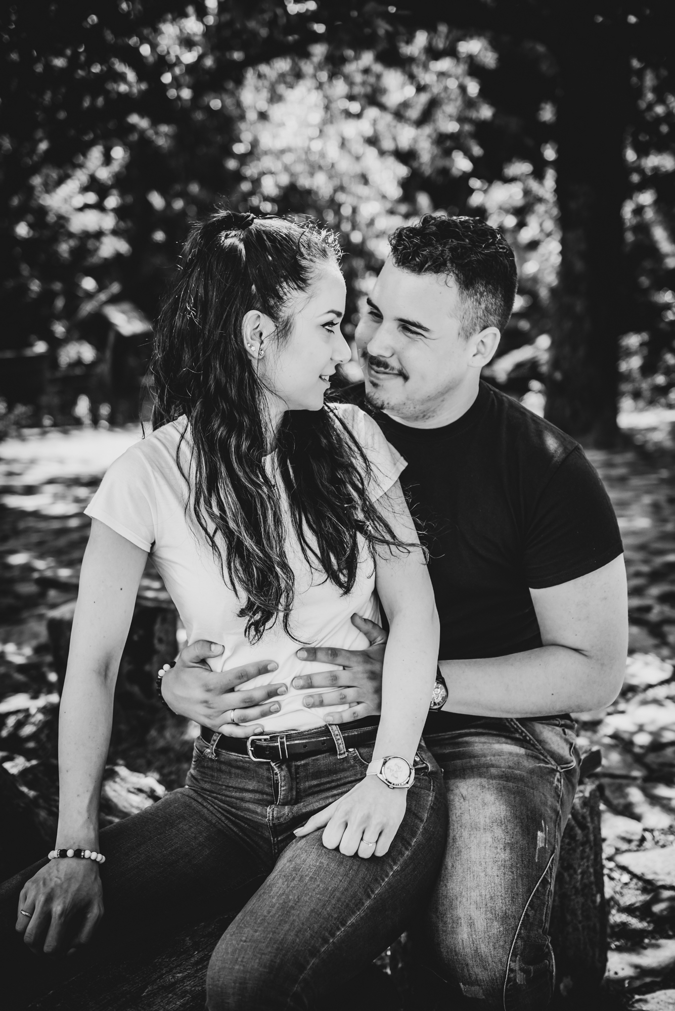 Close black and white portrait of couple sitting together, smiling softly during relaxed engagement session.