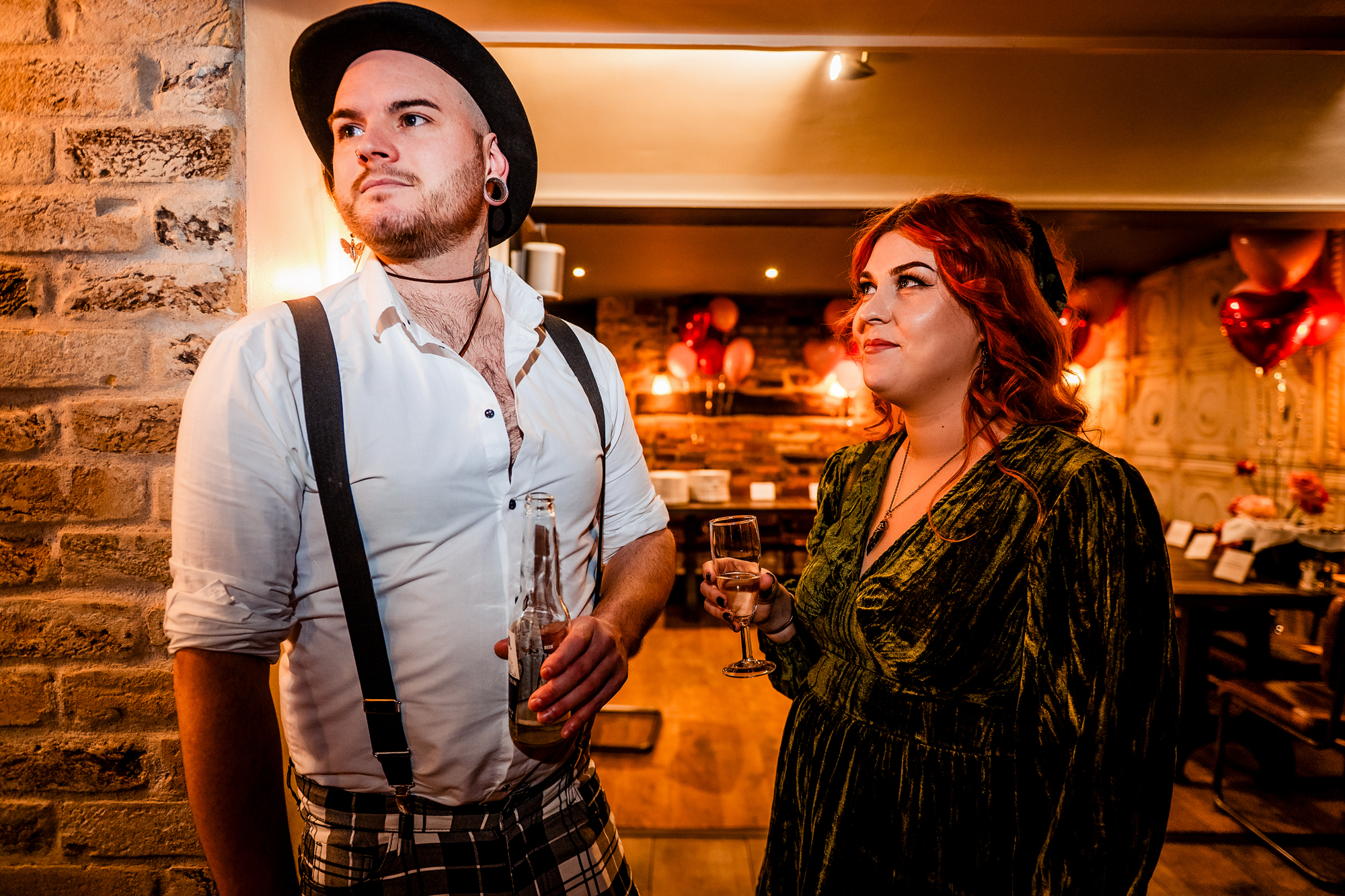 Two guests standing with drinks in the warmly lit Playroom at Racks Bar & Kitchen.