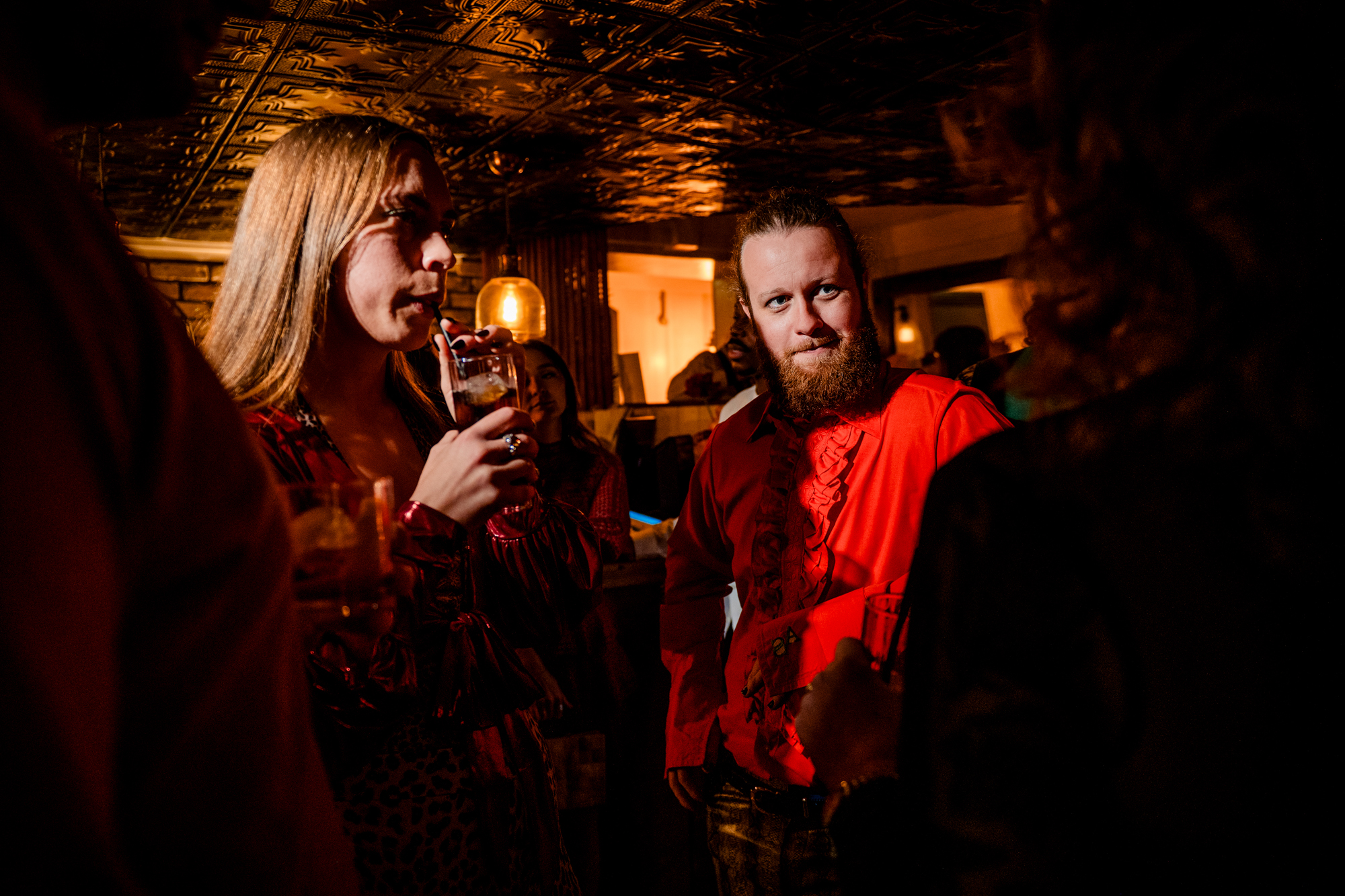Guest in a red shirt illuminated by warm party lighting inside the Playroom at Racks Bristol.