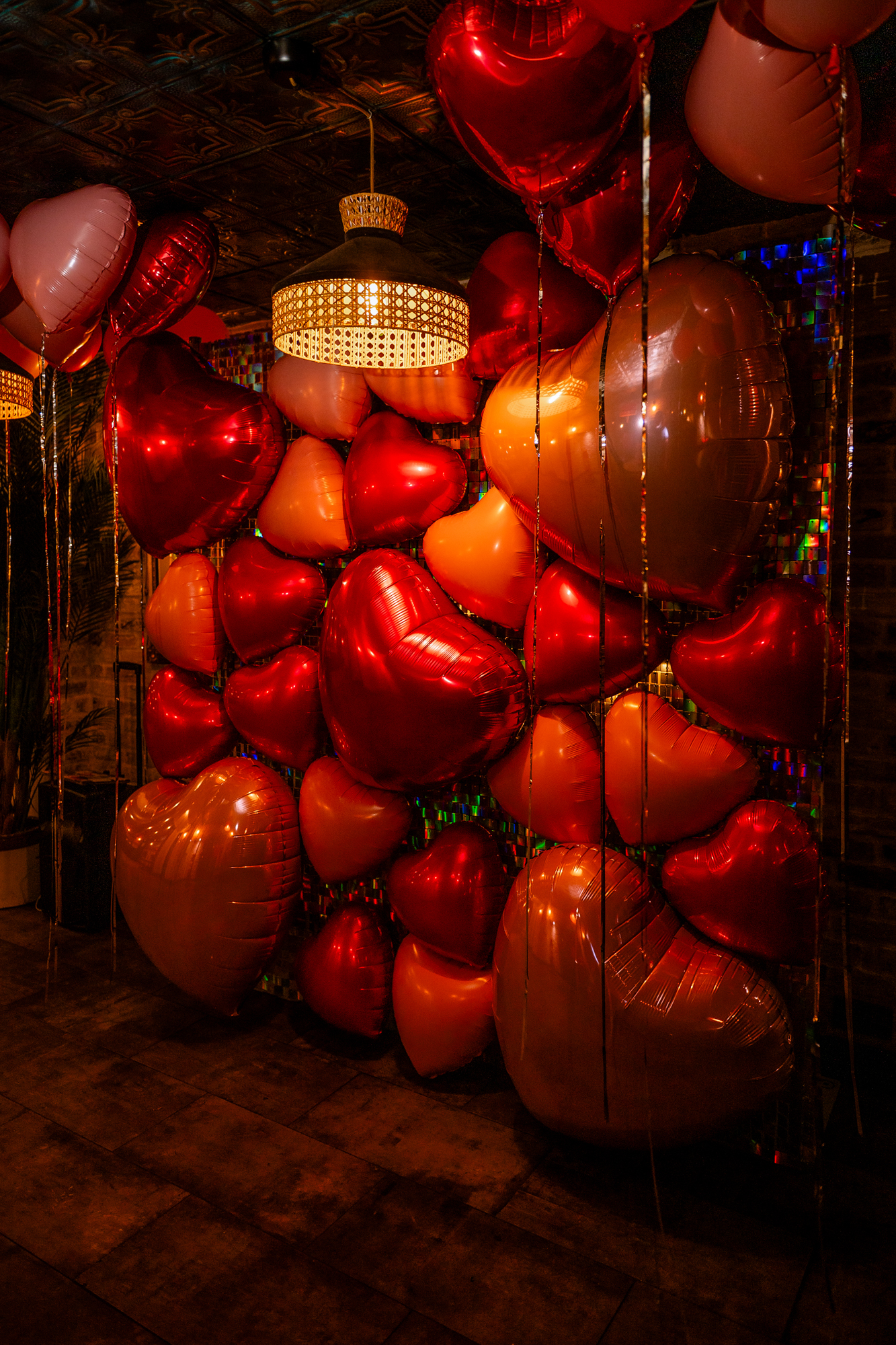 Red and pink heart balloons fill the Playroom at Racks Bristol with warm, moody light.