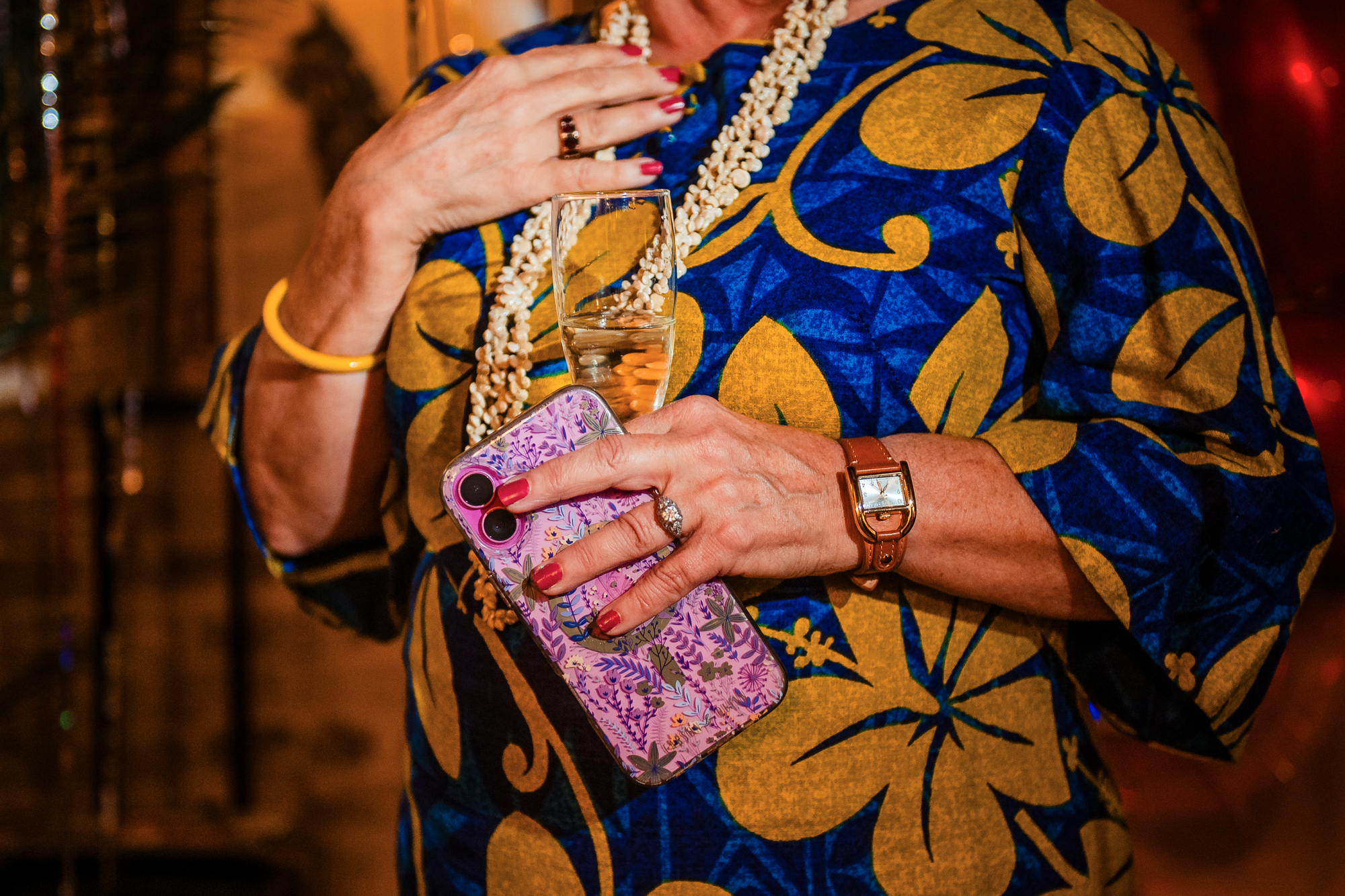 Close-up of a guest holding champagne and a floral phone case during the celebration.