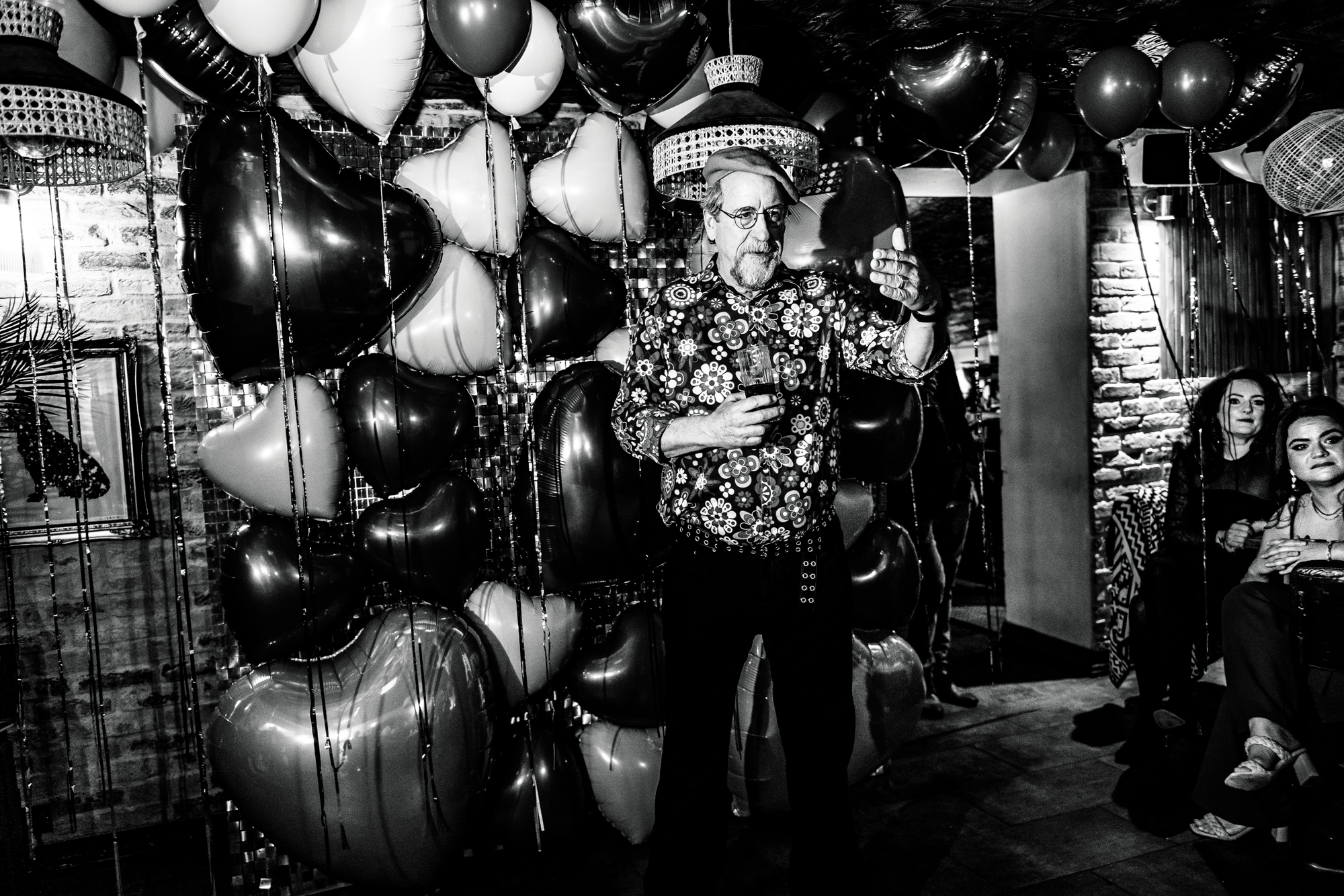 Older guest giving a speech in front of heart balloons.