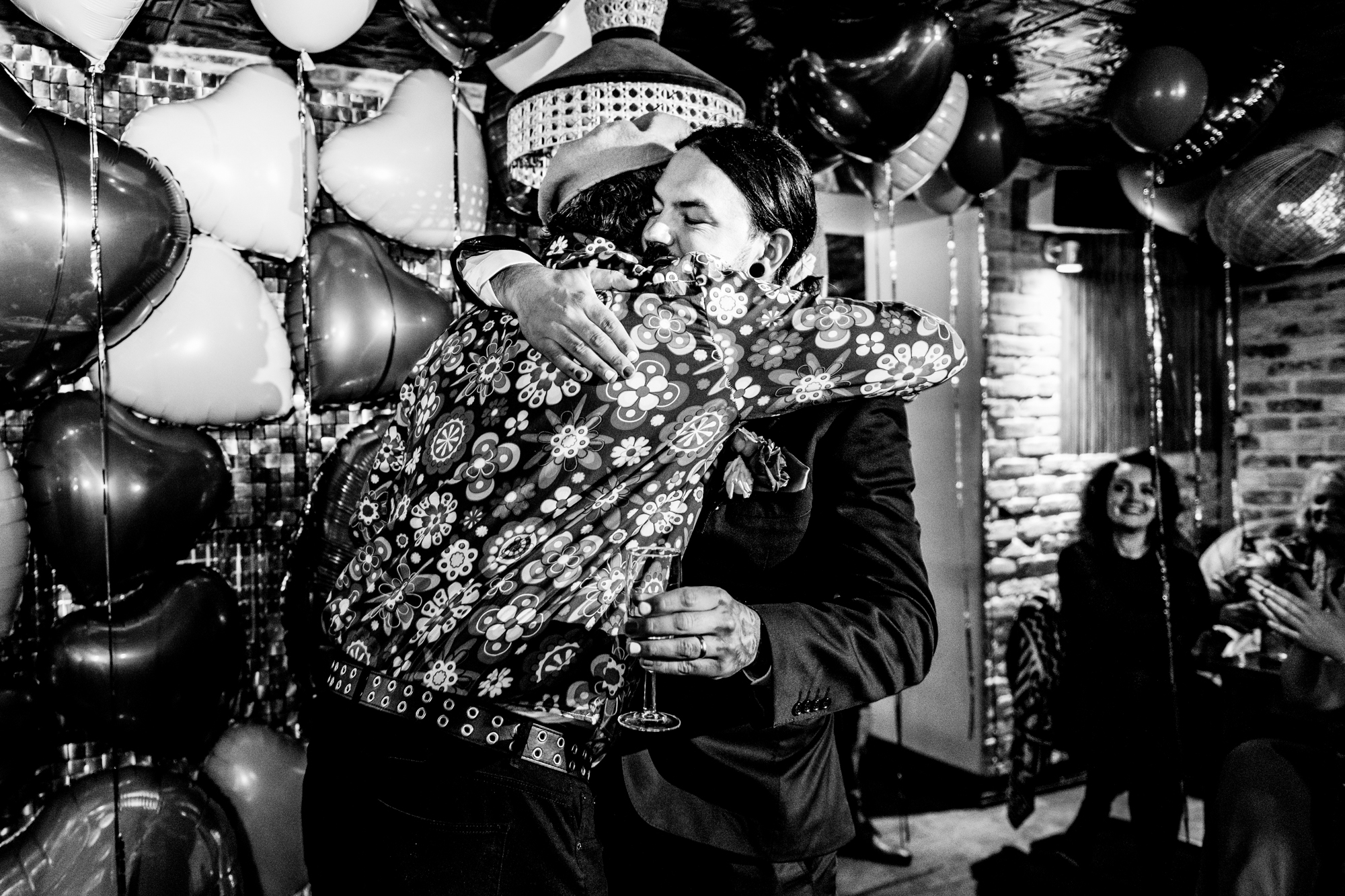 Emotional hug during the speeches in black and white at the wedding party.