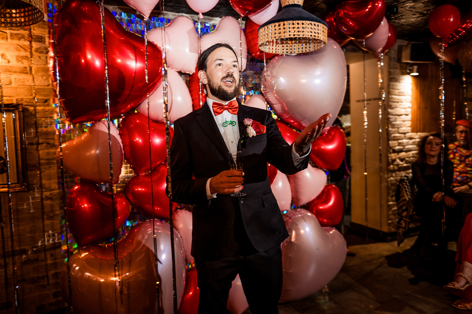 Groom giving a speech in front of the heart balloon backdrop at Racks Bristol.
