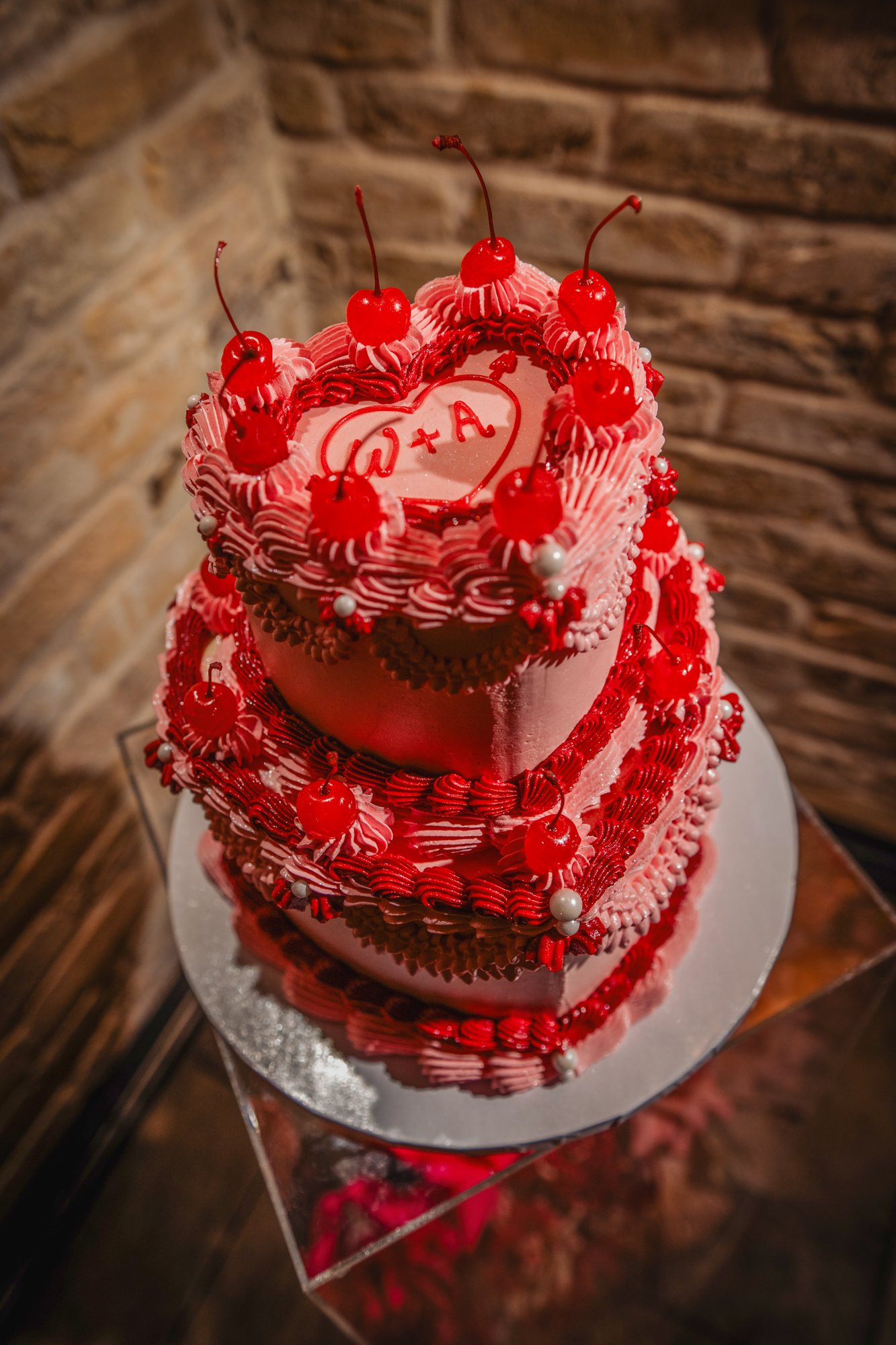 Heart-shaped pink wedding cake with cherries and W + A icing at Racks Bristol.
