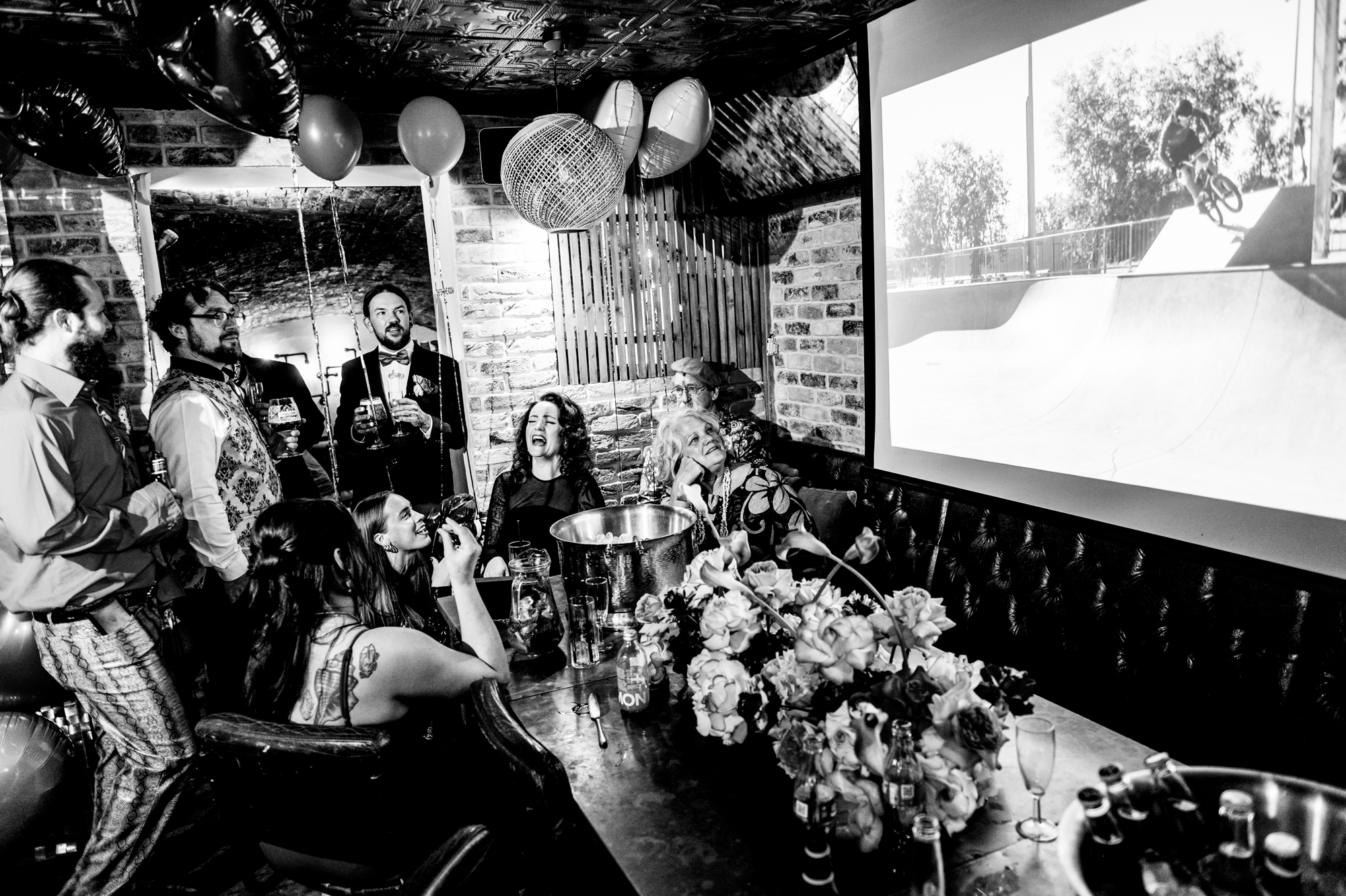 Guests react to a BMX video during speeches at the wedding party.