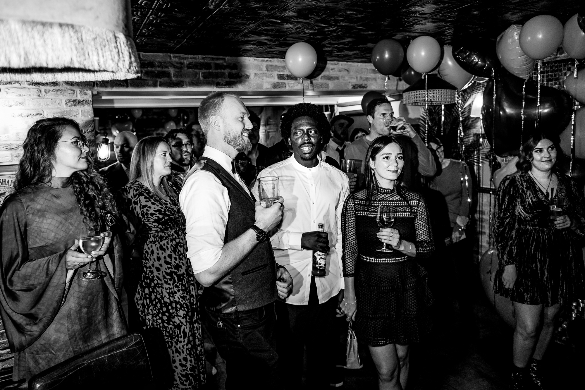 Guests watch the speeches and smile beneath heart balloons in the Playroom.