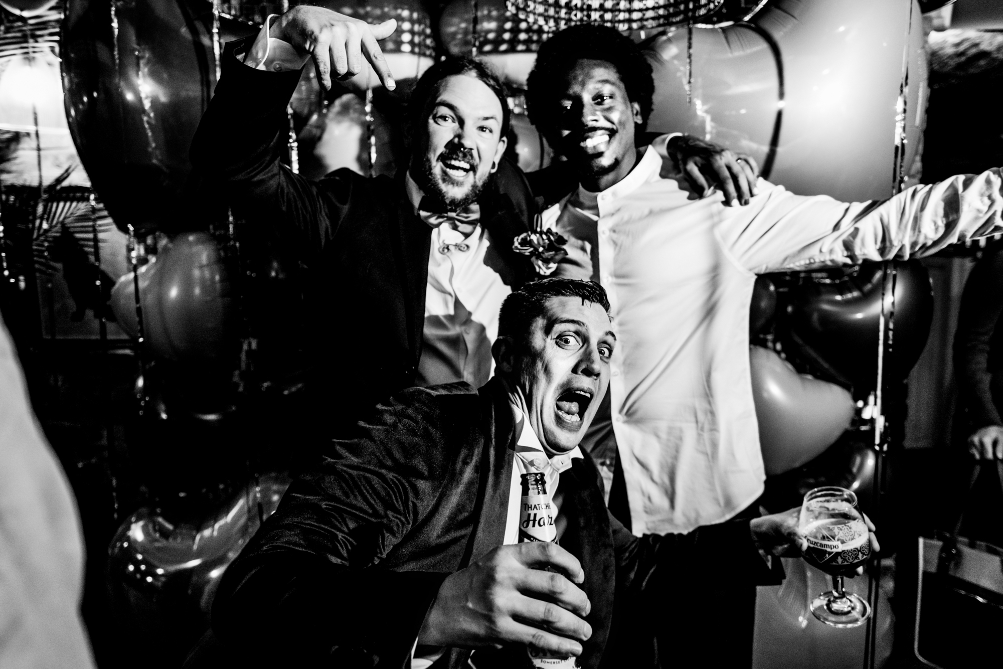 Guests with the groom laugh together during the evening wedding party.