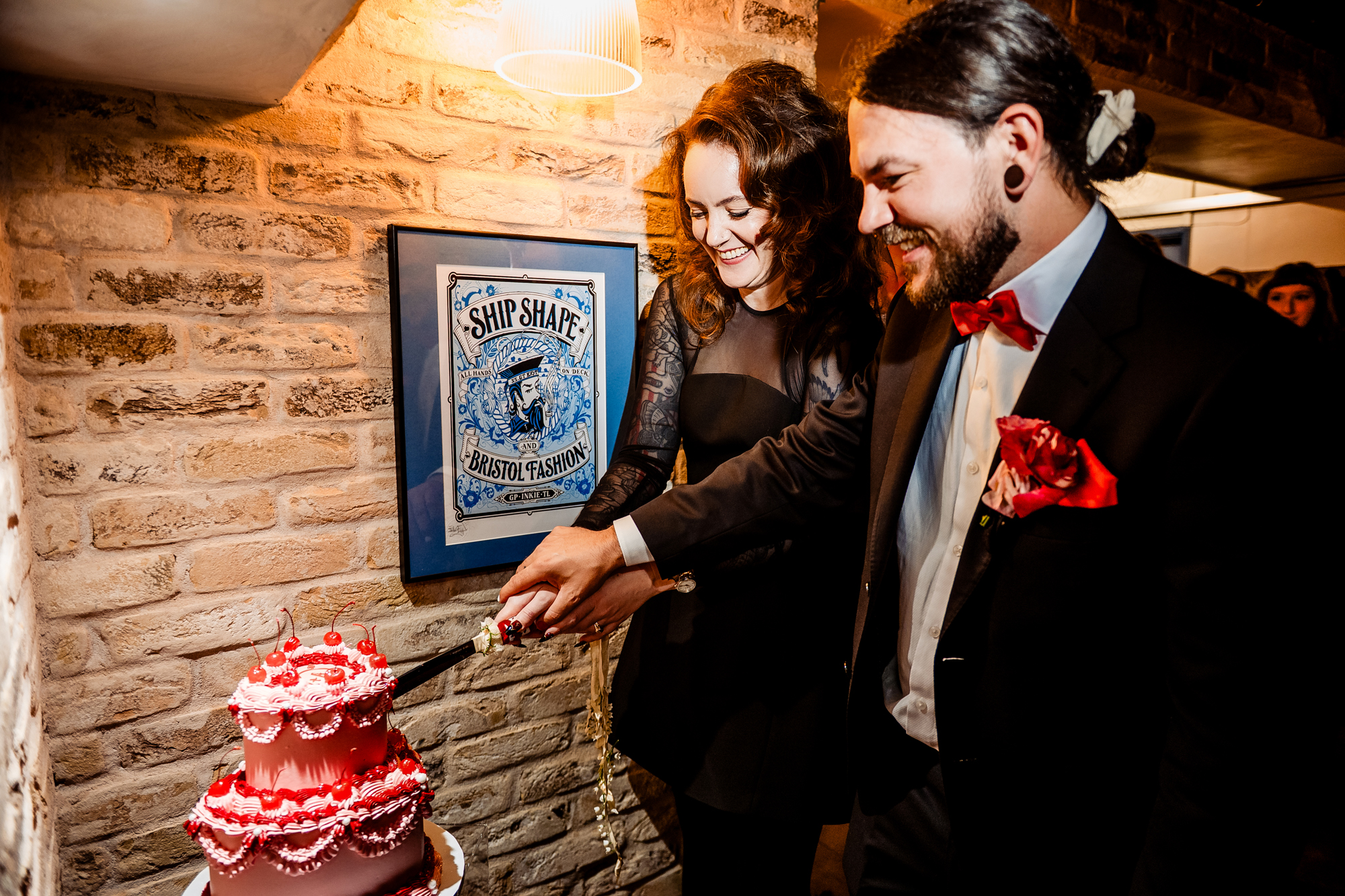 Couple cutting their cherry-topped pink wedding cake together at Racks Bristol.