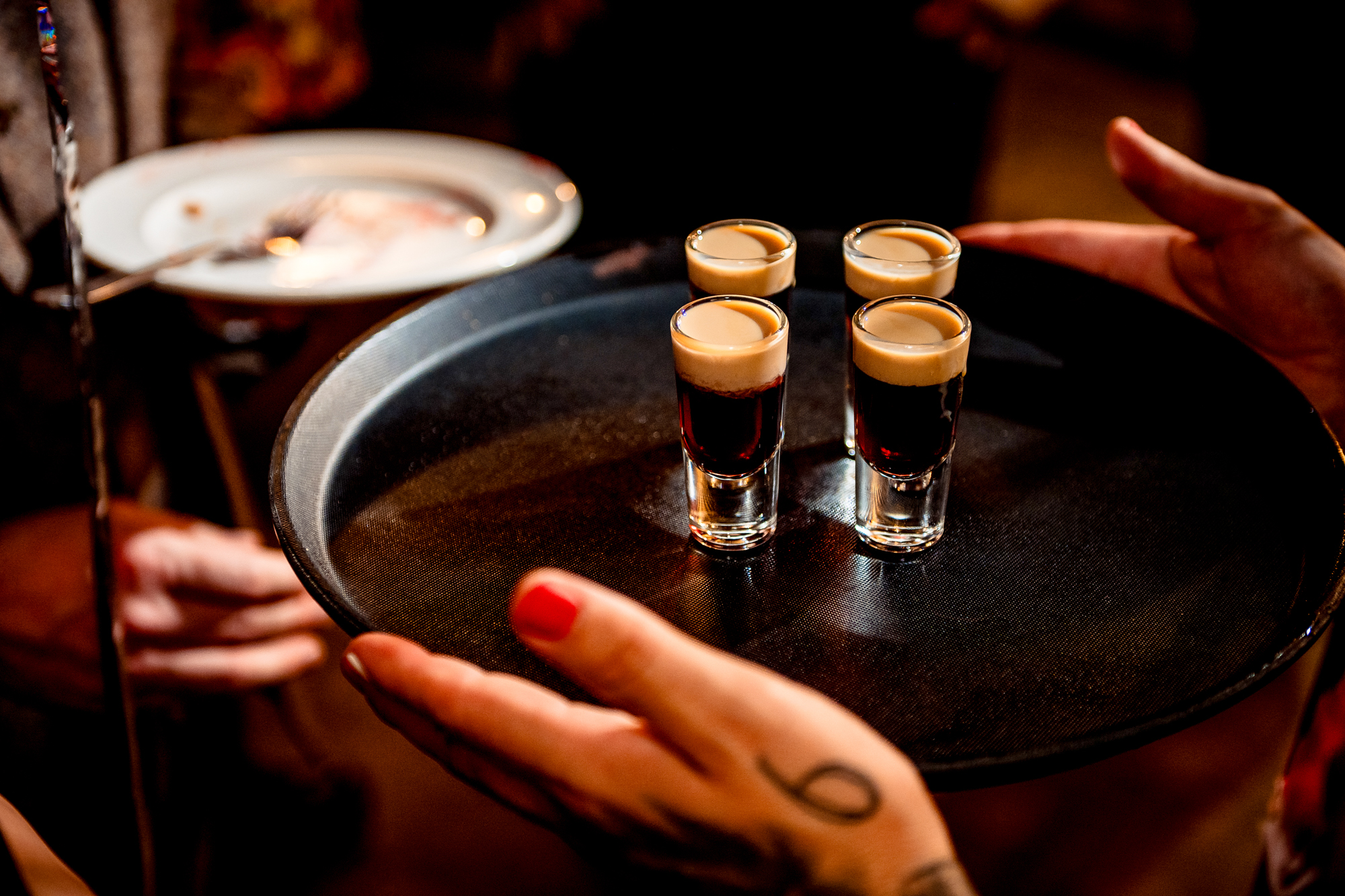 Four baby guiness shots balanced on a tray during the evening wedding party.