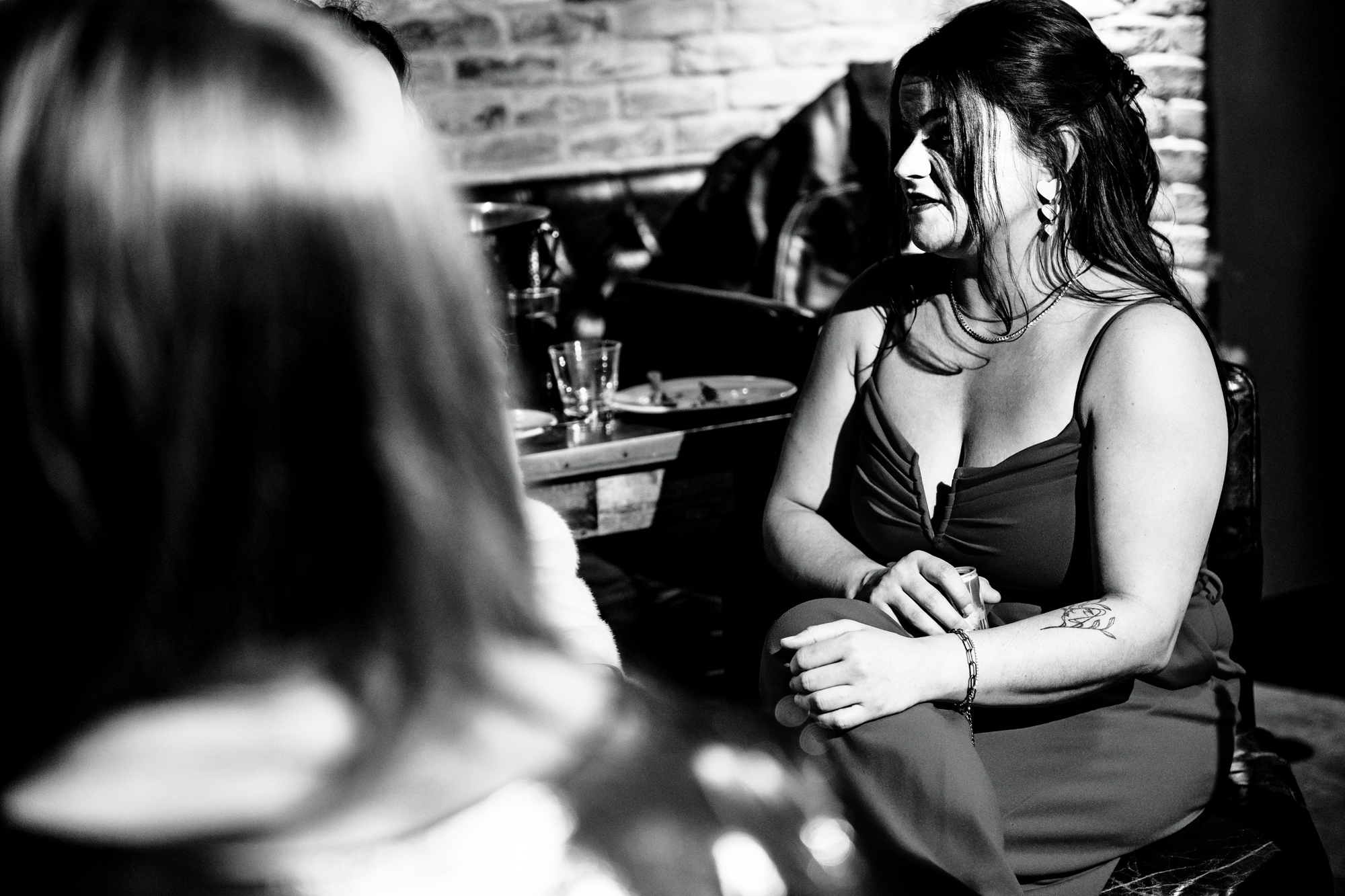 Guest sitting and smiling softly in black and white during the evening celebration.