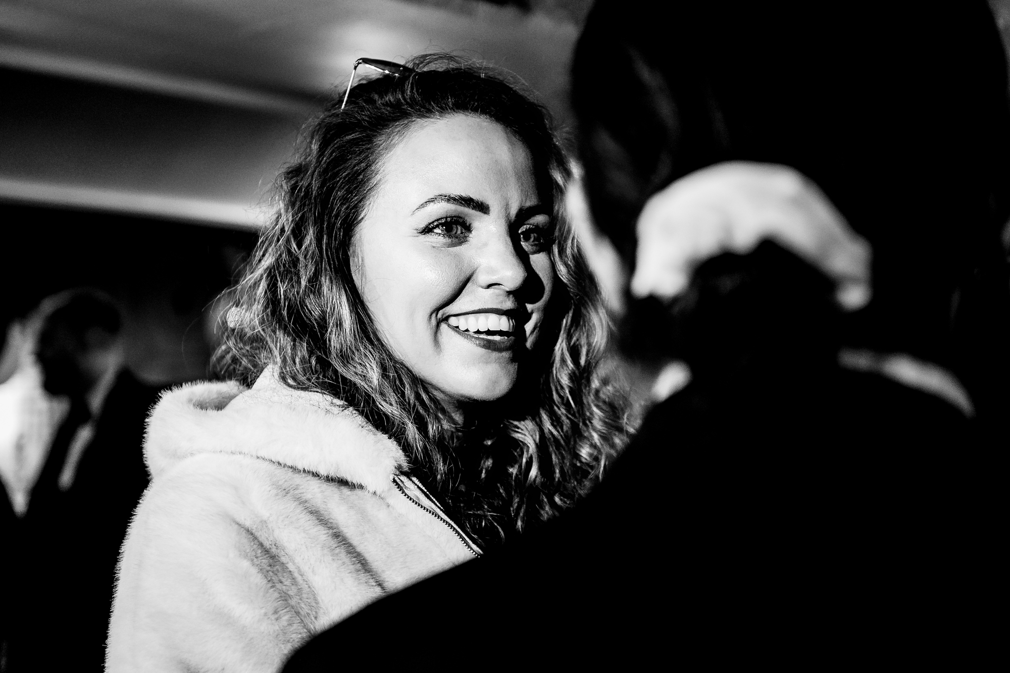 Guest smiling over someone’s shoulder during the wedding party.