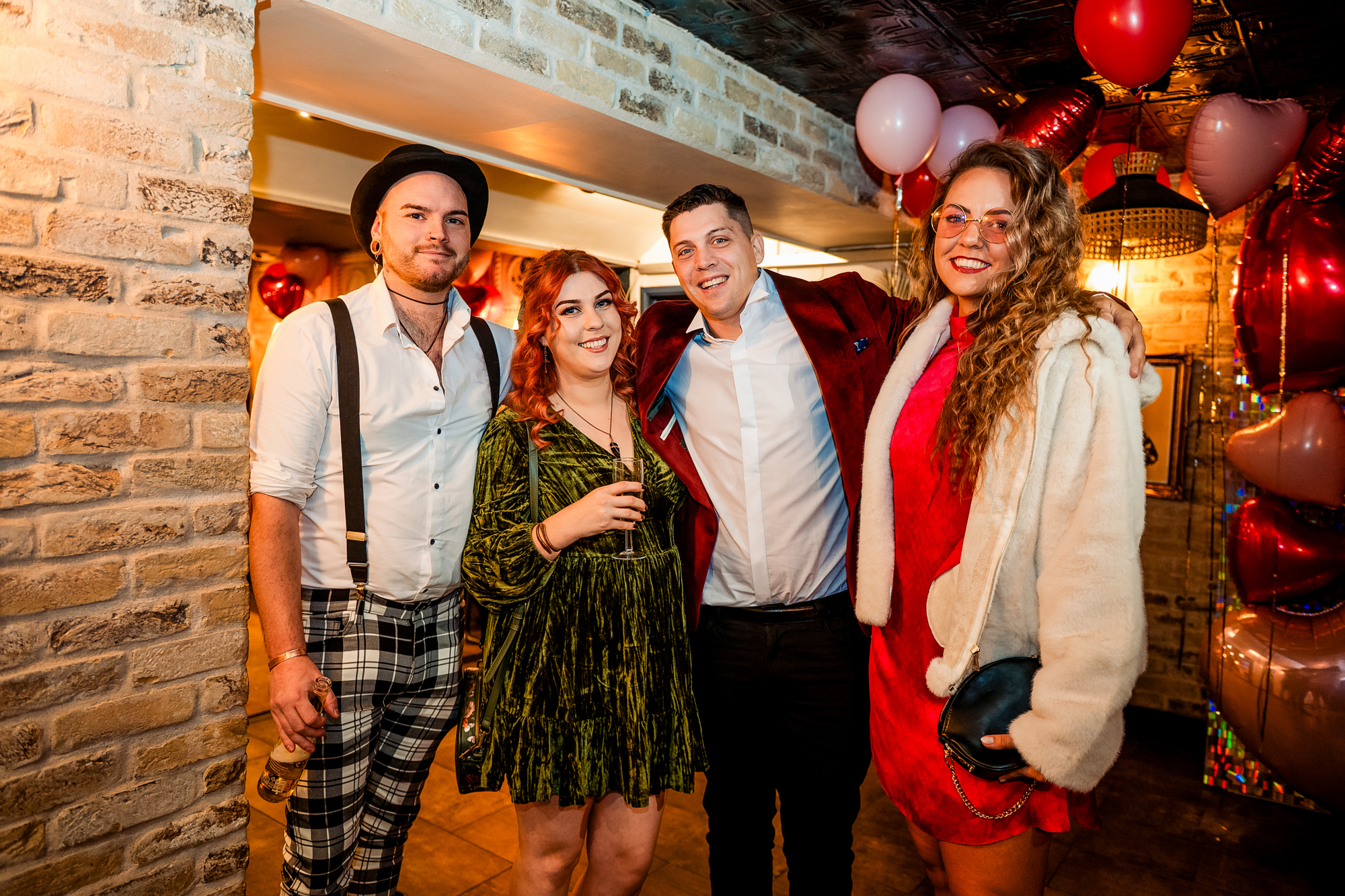 Stylish wedding guests posing together inside the warm, candlelit Playroom at Racks Bristol.