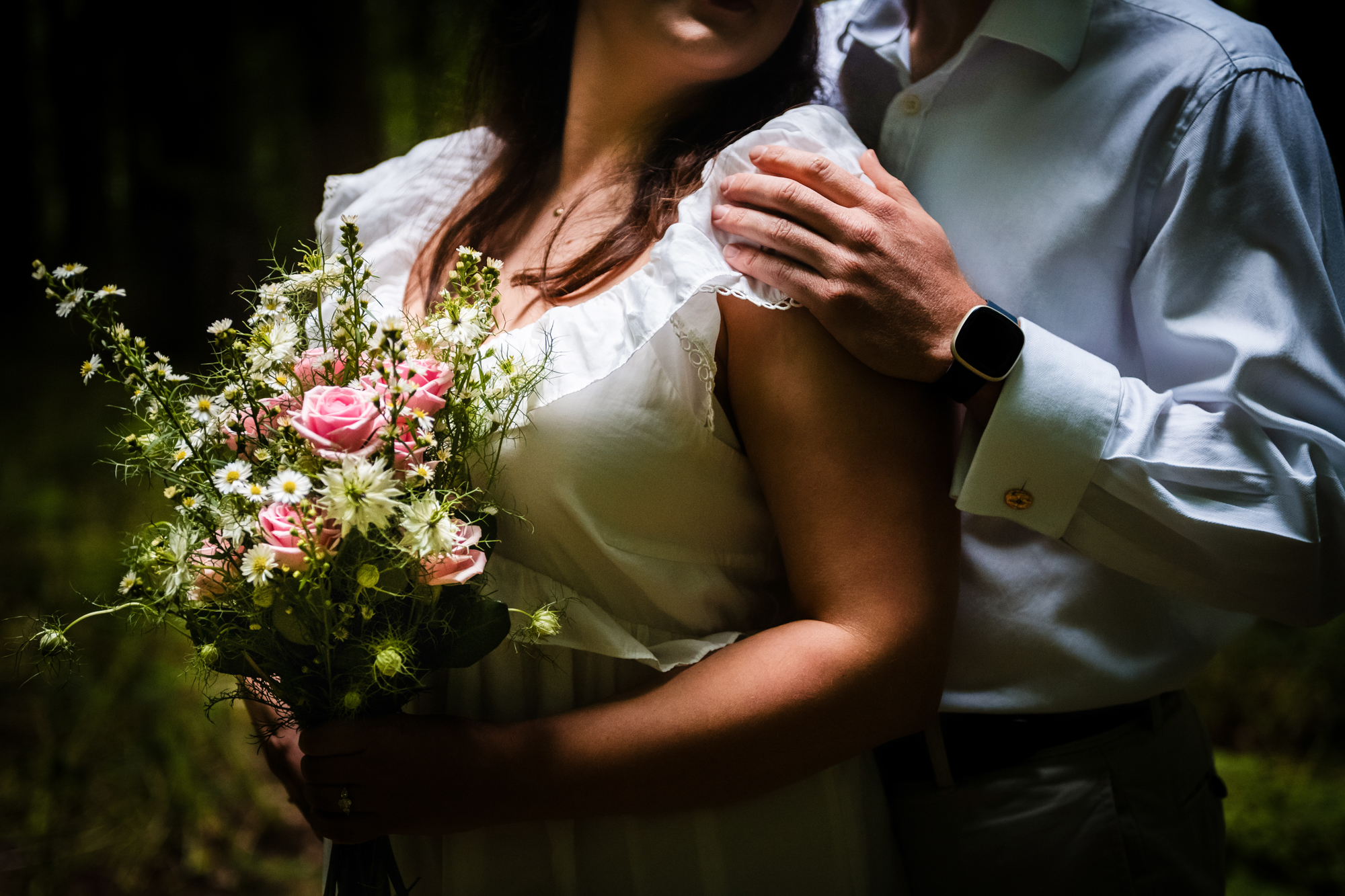 Close-up of bouquet and couple during a romantic woodland engagement photo session.