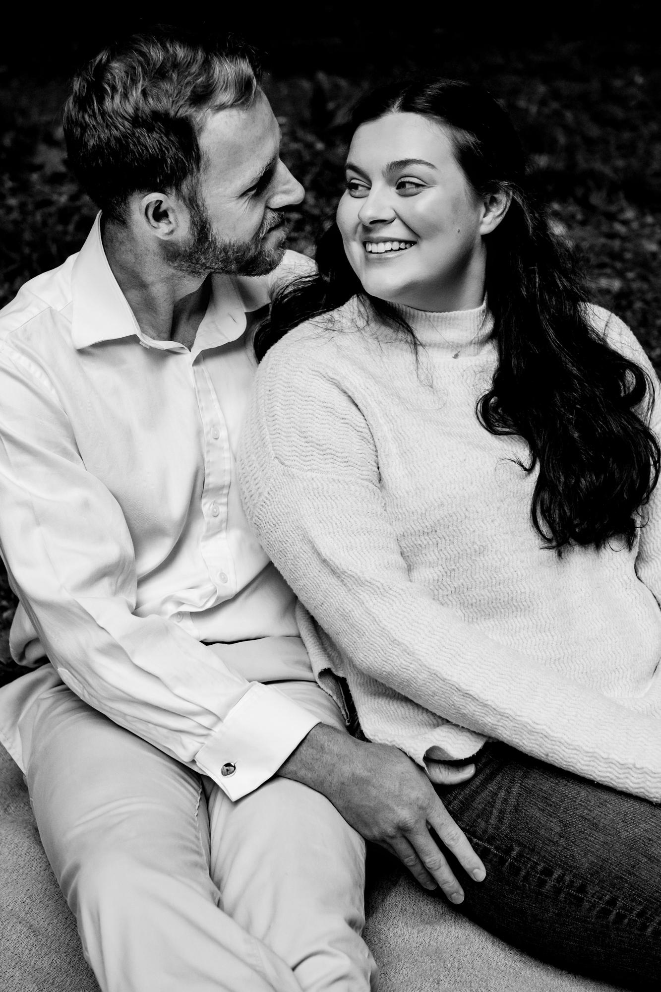 Candid moment of couple smiling at each other while sitting close together.