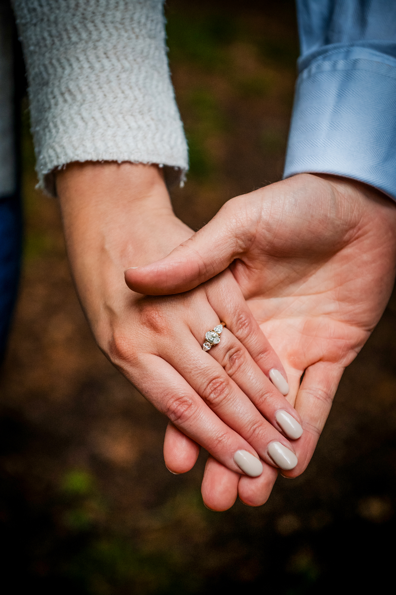 Close-up of the couple holding hands, with the engagement ring clearly visible.