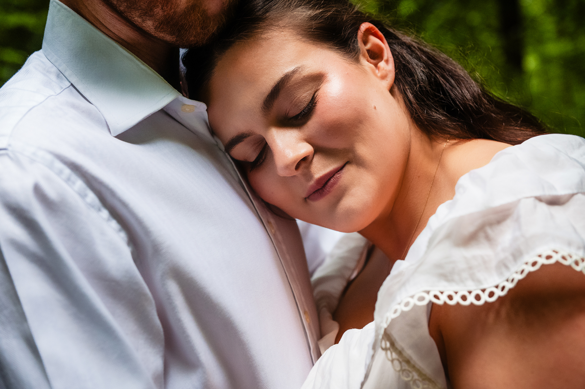 Close portrait of the bride-to-be resting against her partner during a woodland engagement shoot.