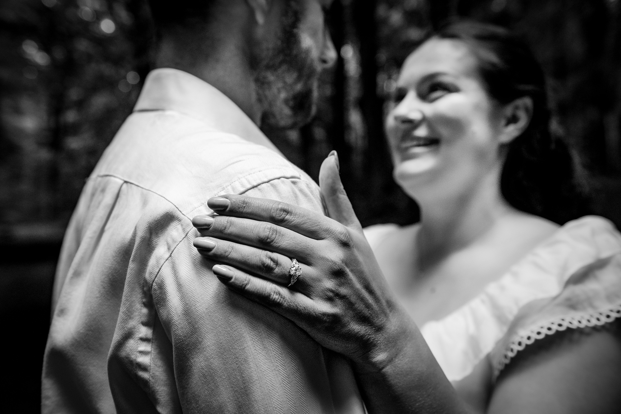 Close-up of an engagement ring resting on a shoulder during a black and white portrait.