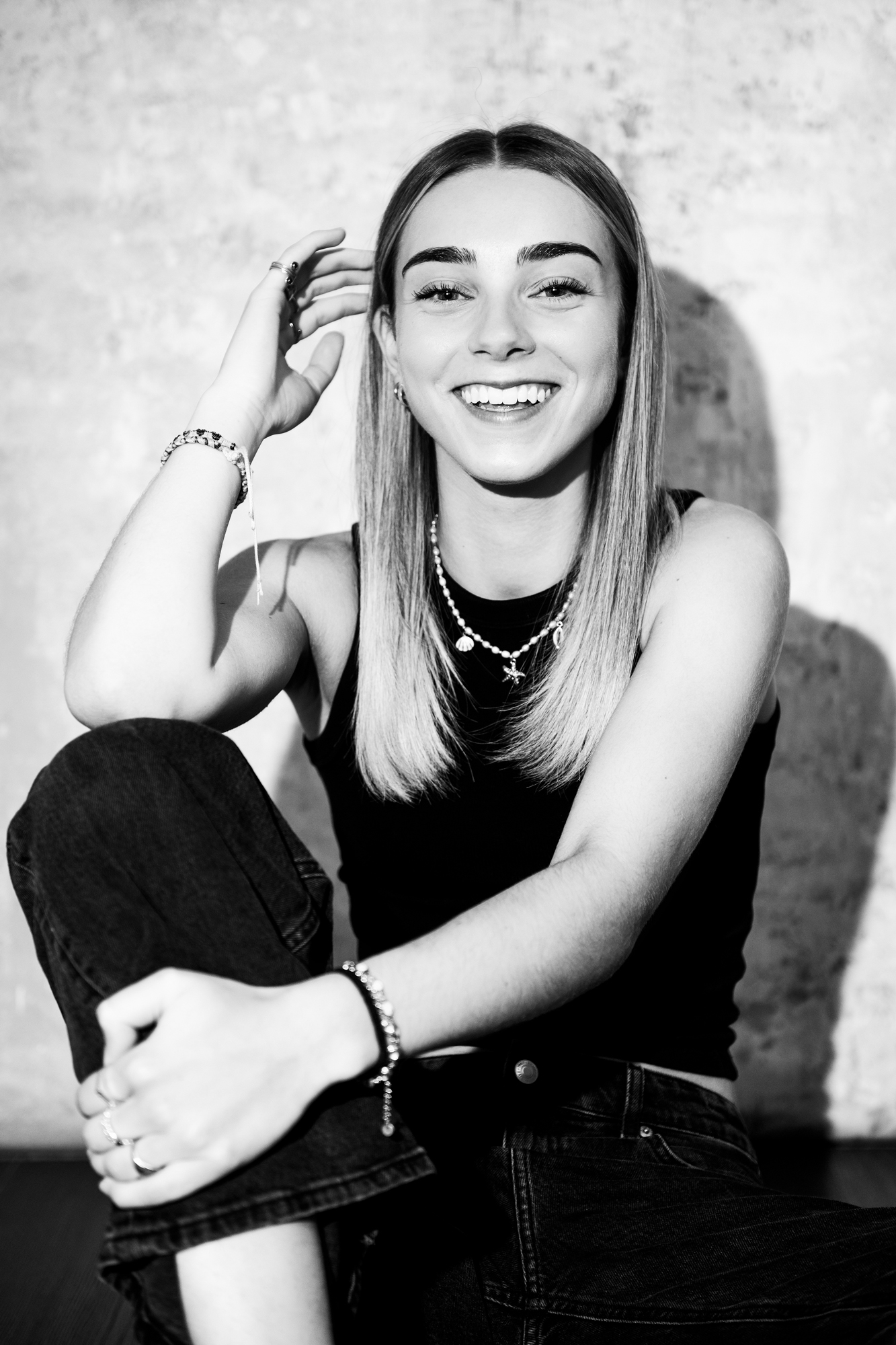 Black and white portrait of smiling young woman sitting casually during Bristol studio portrait session.