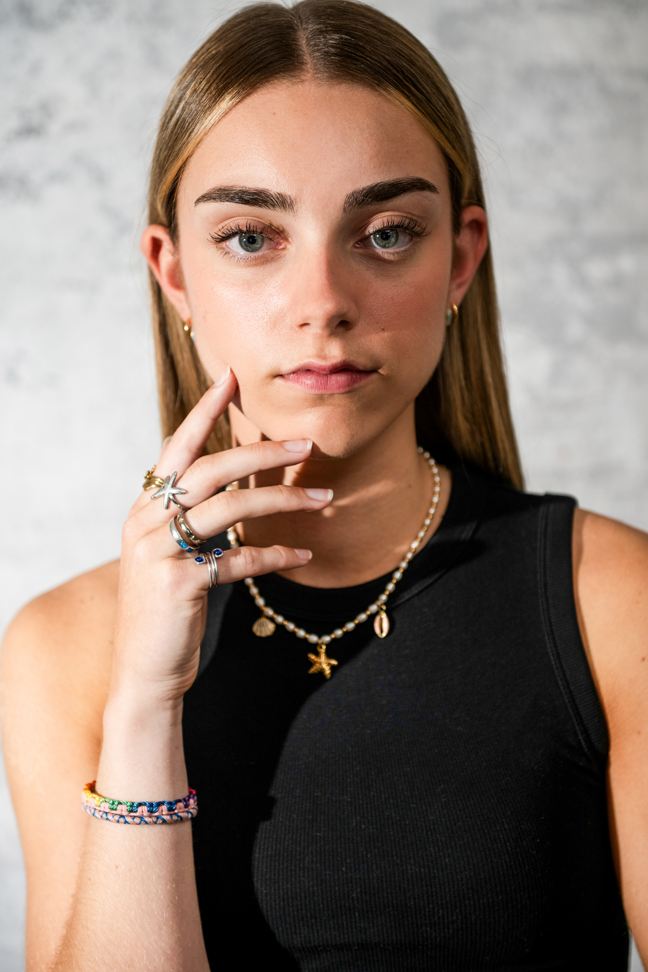 Model portrait with direct eye contact and layered shell jewellery in Bristol portrait studio.