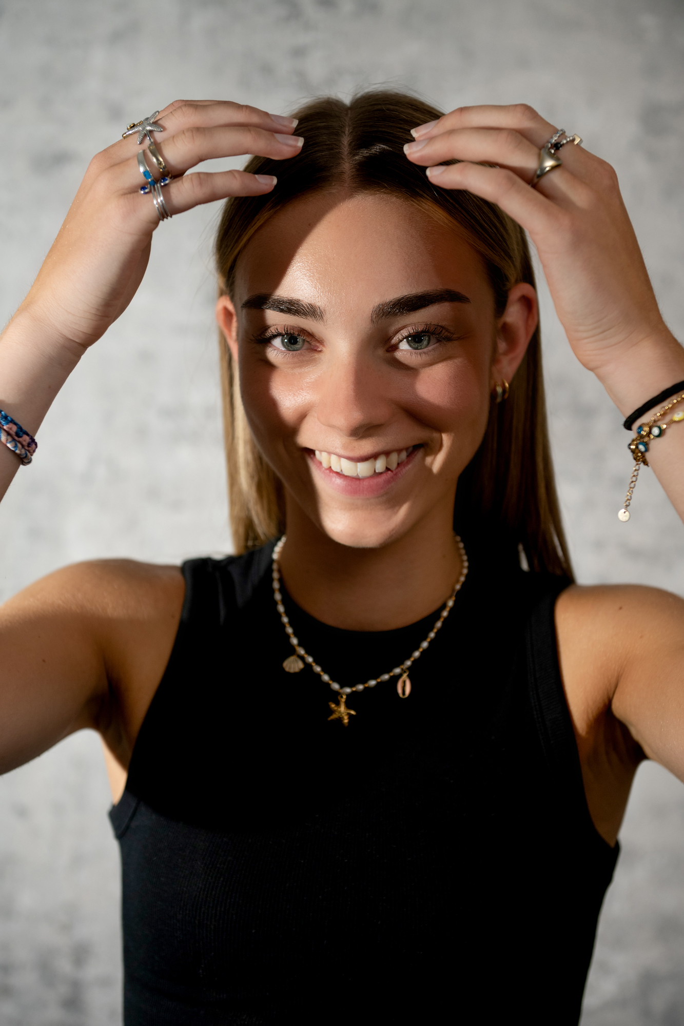 Smiling young woman adjusting her hair during natural light studio portrait session in Bristol.