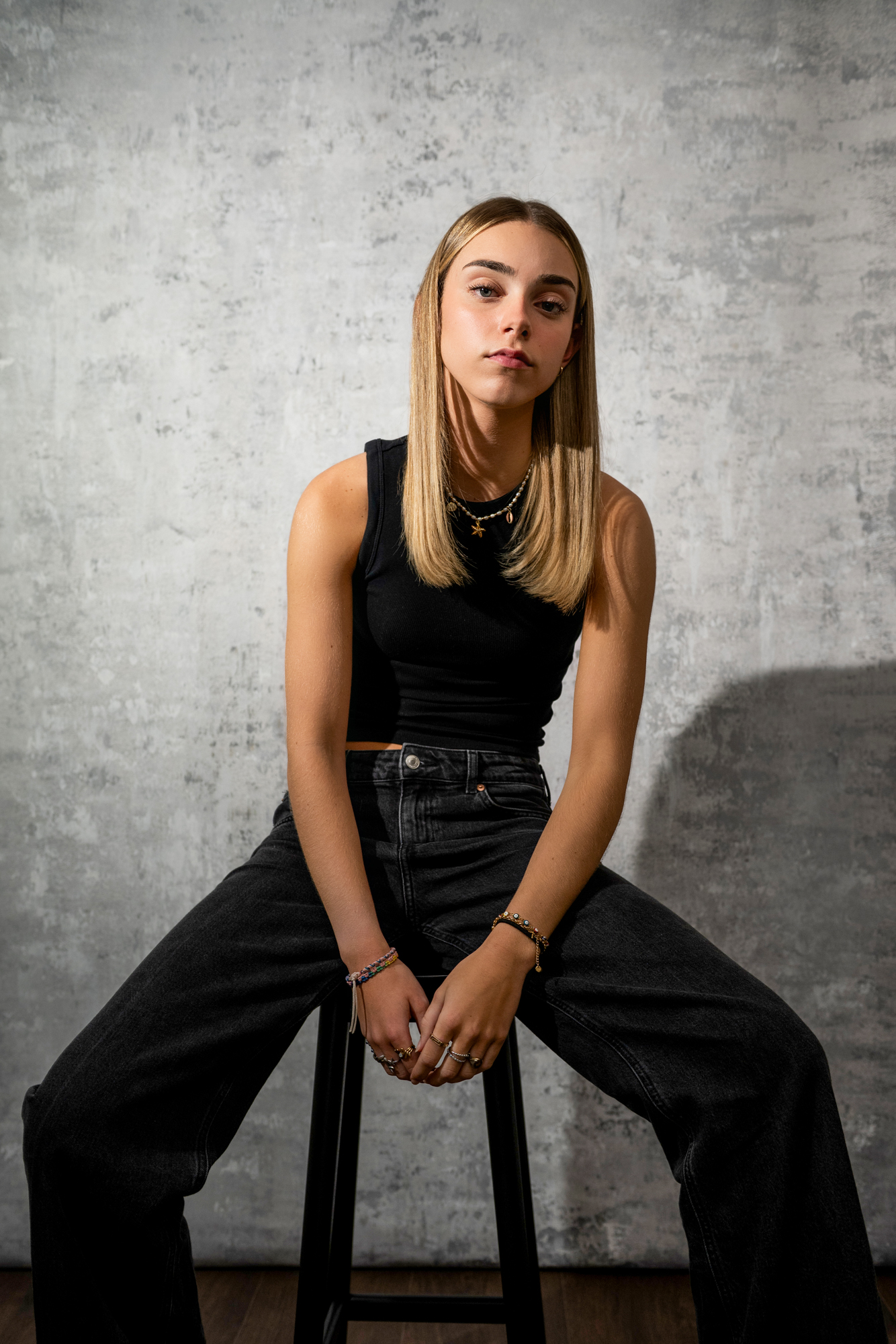 Moody fashion-inspired portrait of woman sitting on stool in Bristol photography studio.