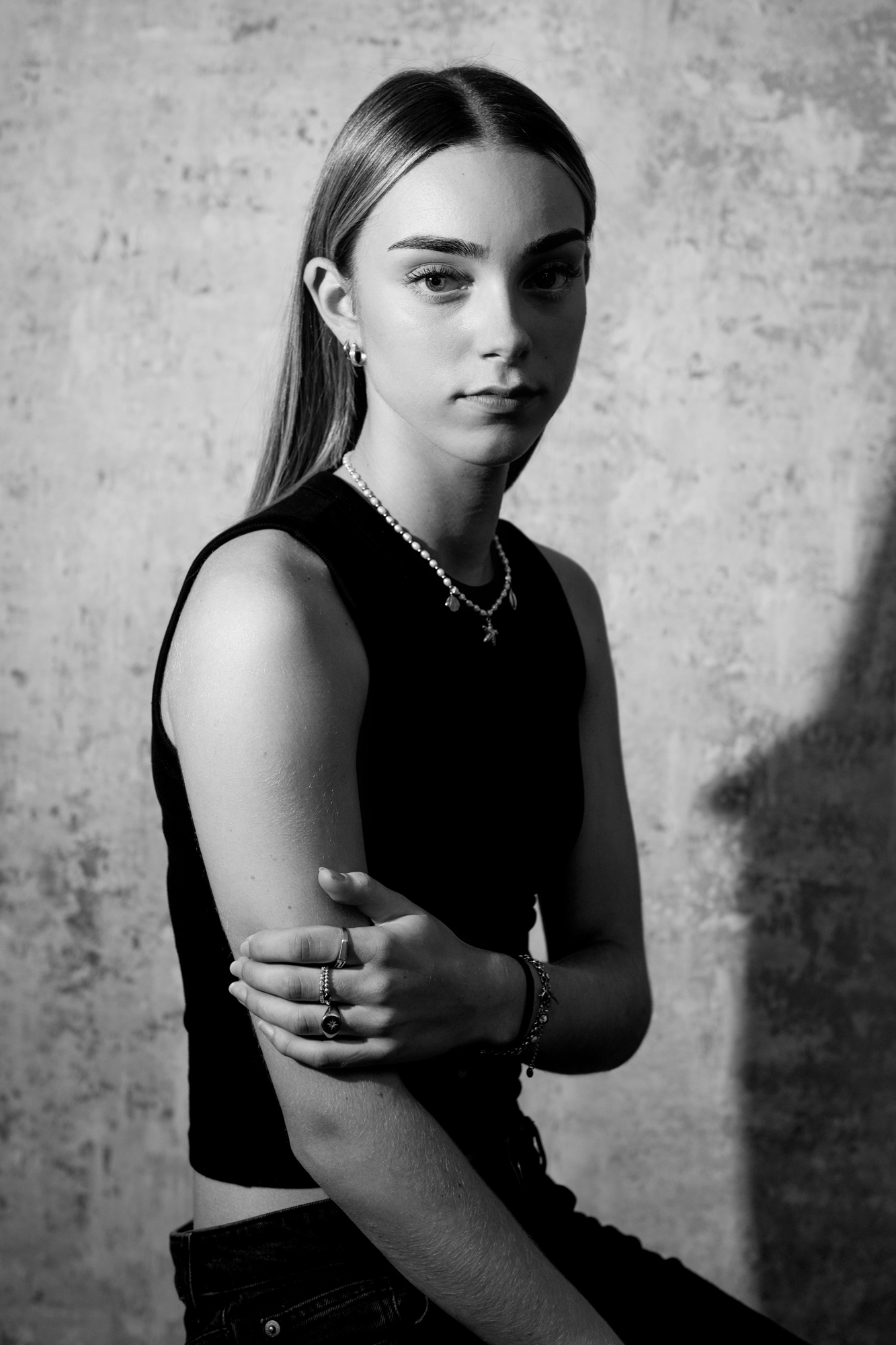 Black and white portrait of young woman with crossed arms and shadow detail in Bristol photography studio.