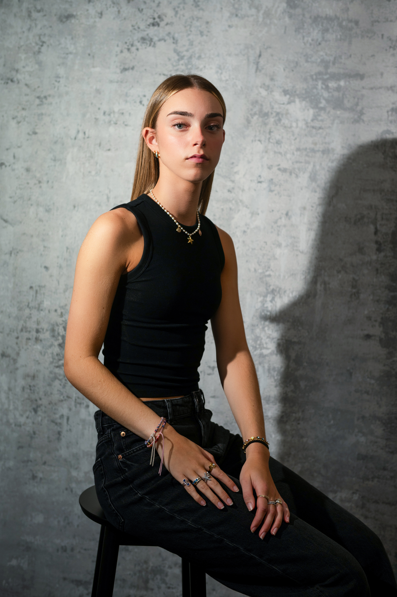 Young woman sitting on stool in black outfit during editorial-style portrait photography session in Bristol.
