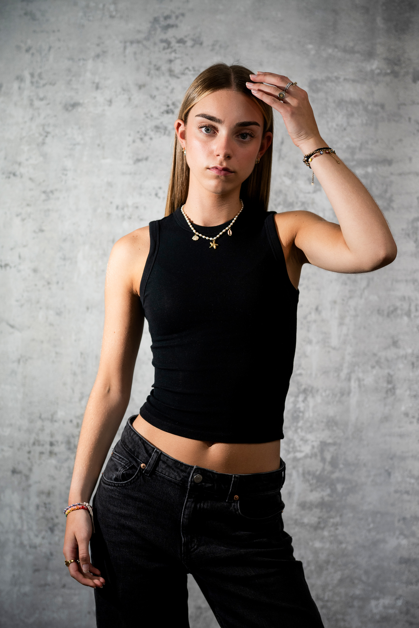 Fashion portrait of young woman adjusting her hair in minimalist Bristol portrait photography studio.