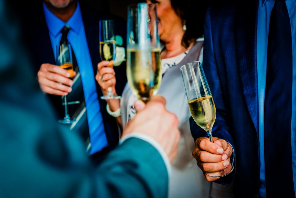 Guests raising champagne glasses during a wedding drinks reception celebration.