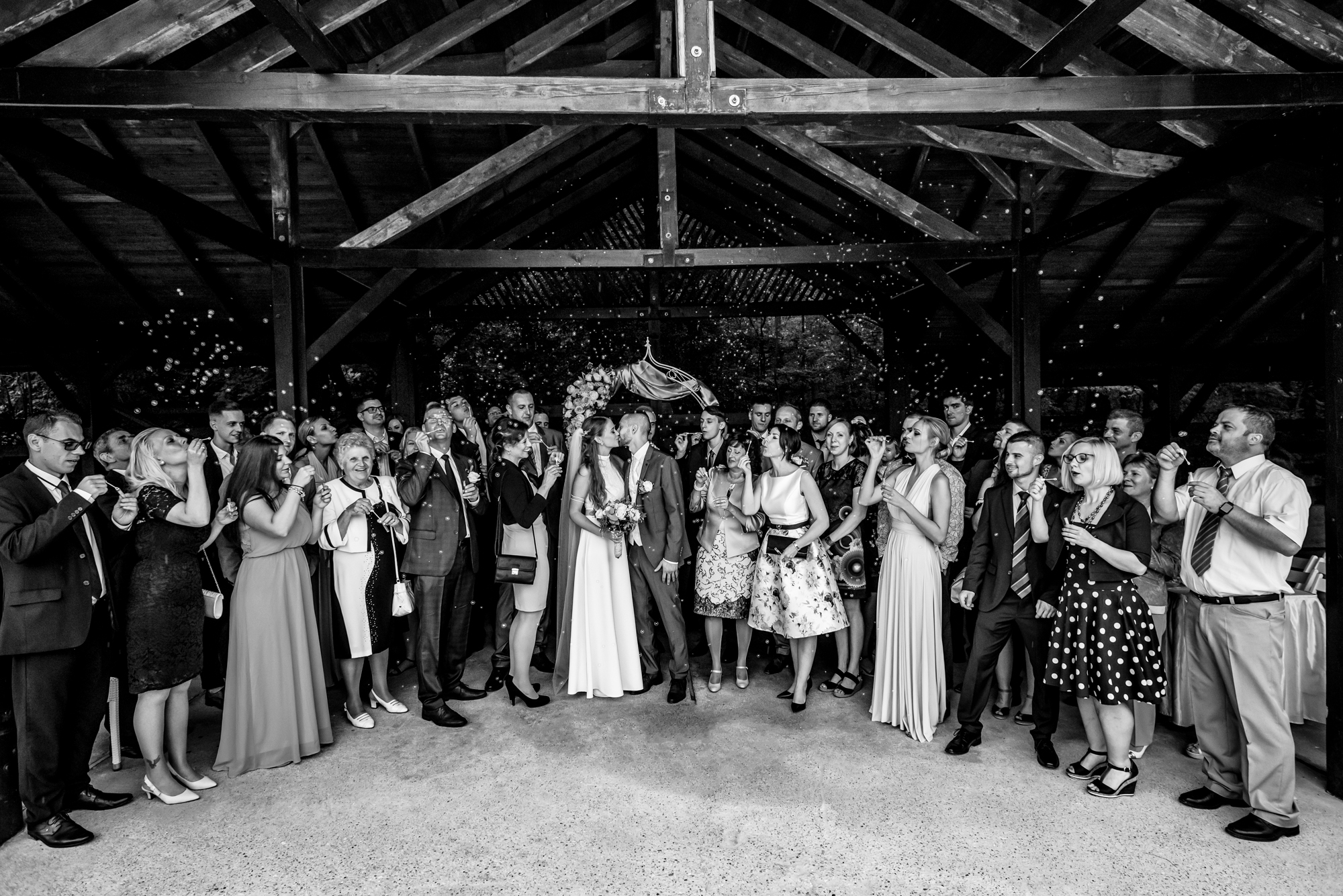Wedding guests surrounding the couple while blowing bubbles after the ceremony.