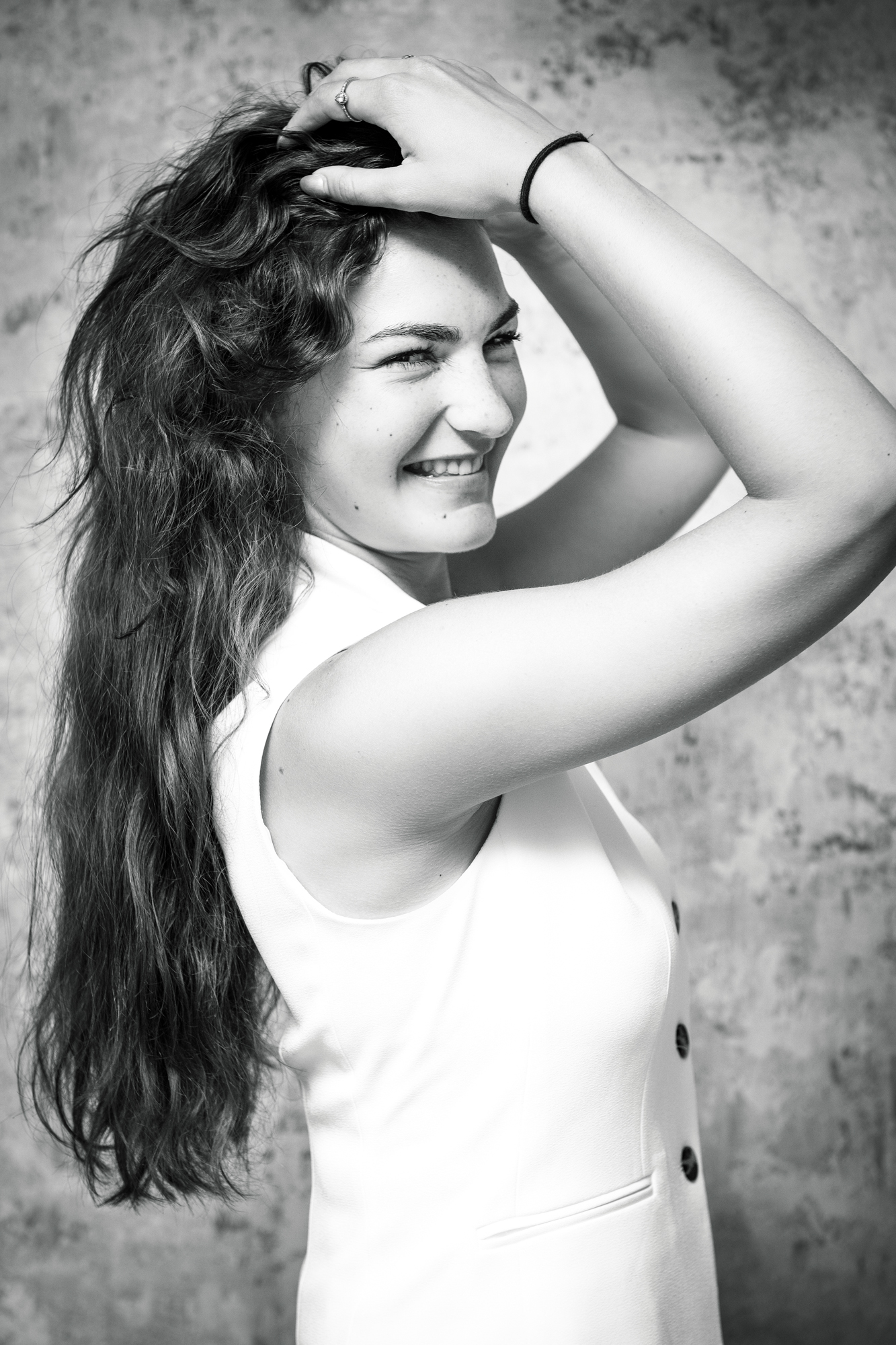 Woman in white dress looking over shoulder during soft natural light studio portrait.