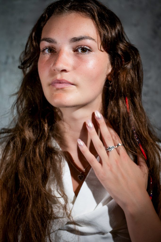 Studio beauty portrait with soft lighting, natural makeup, and hand near face.