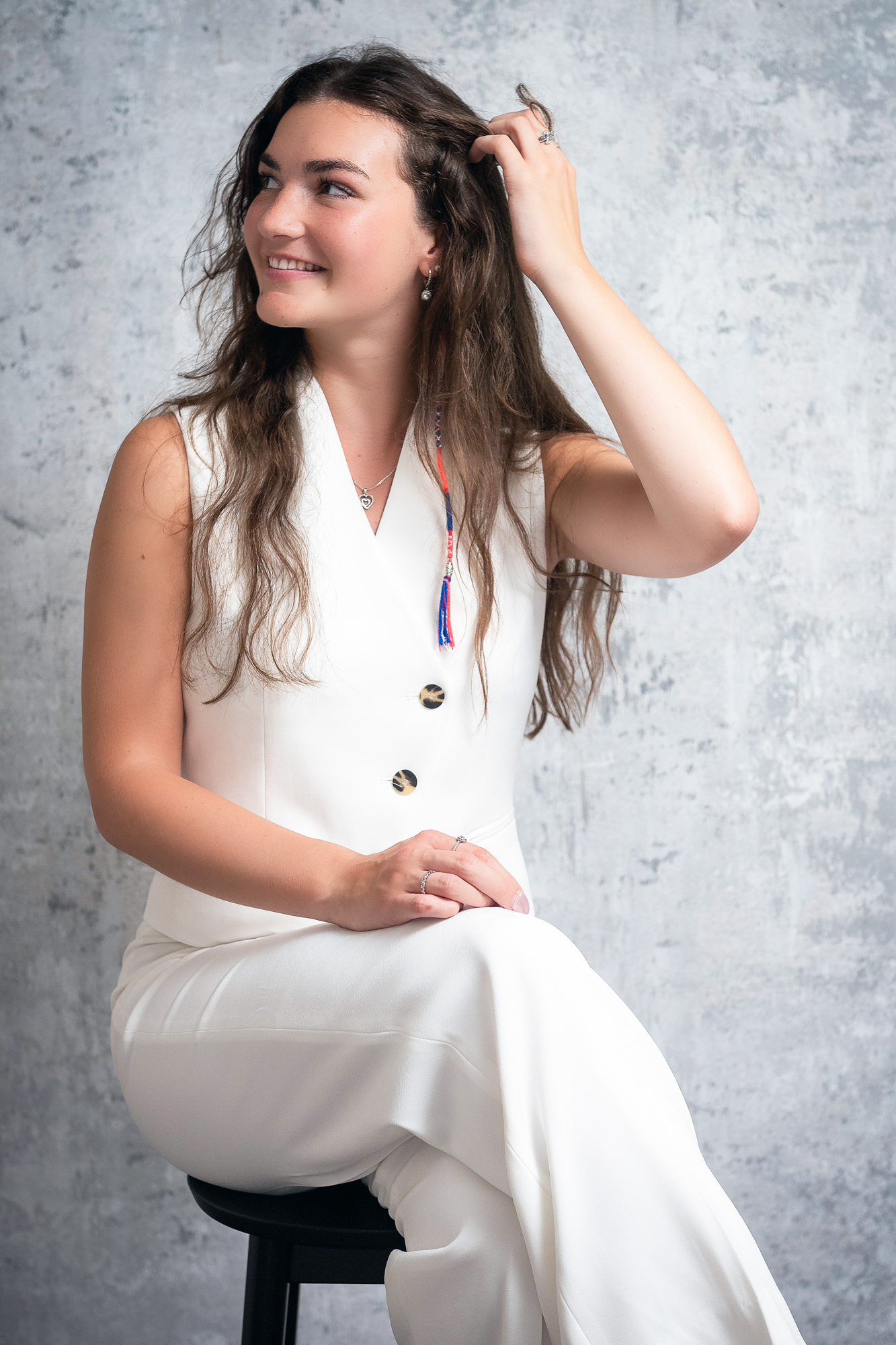 Woman in white sleeveless suit touching her hair during modern branding portrait session.