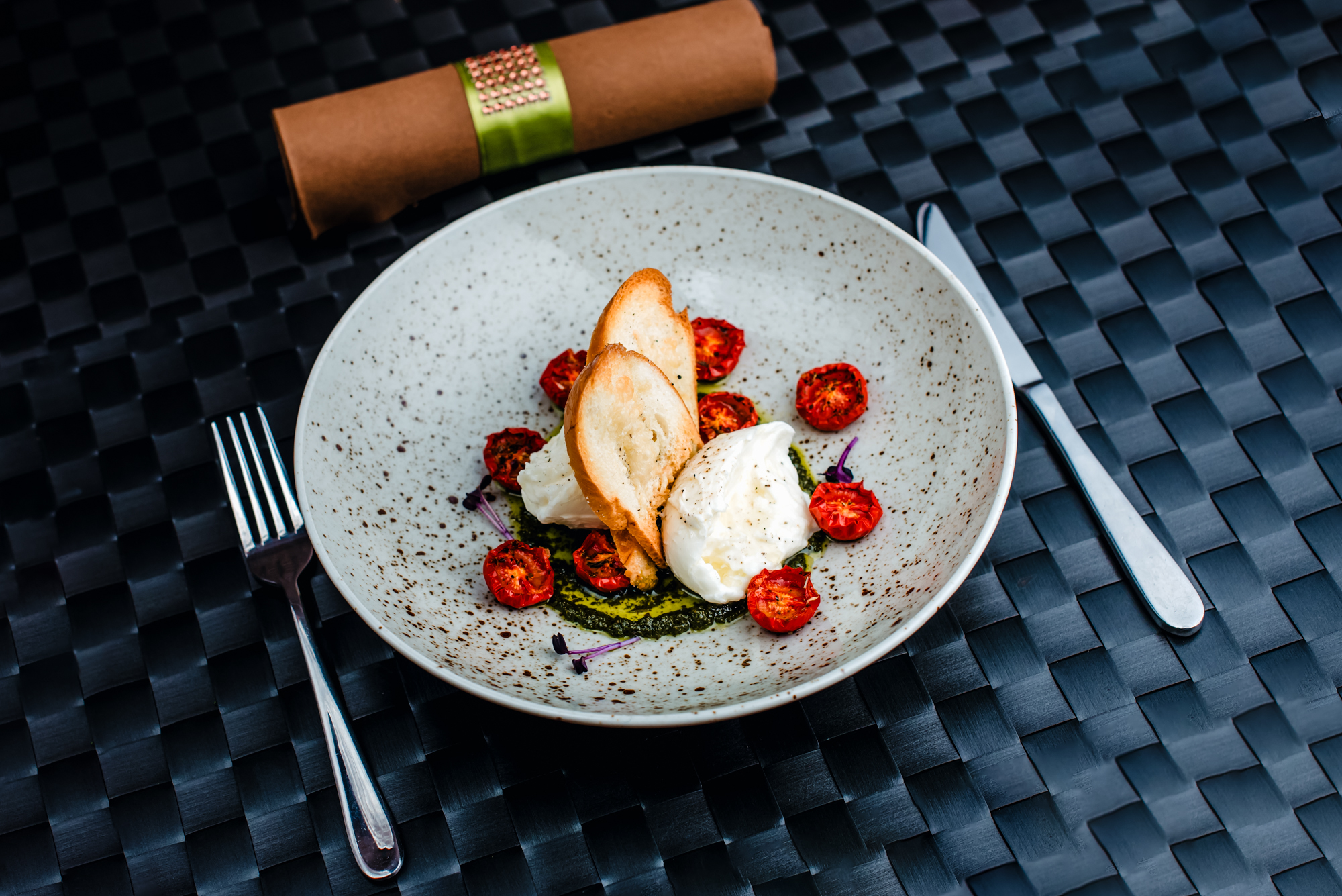 Burrata cheese with roasted cherry tomatoes, pesto, and toasted bread served in a speckled bowl at Rubin Hotel Budapest.
