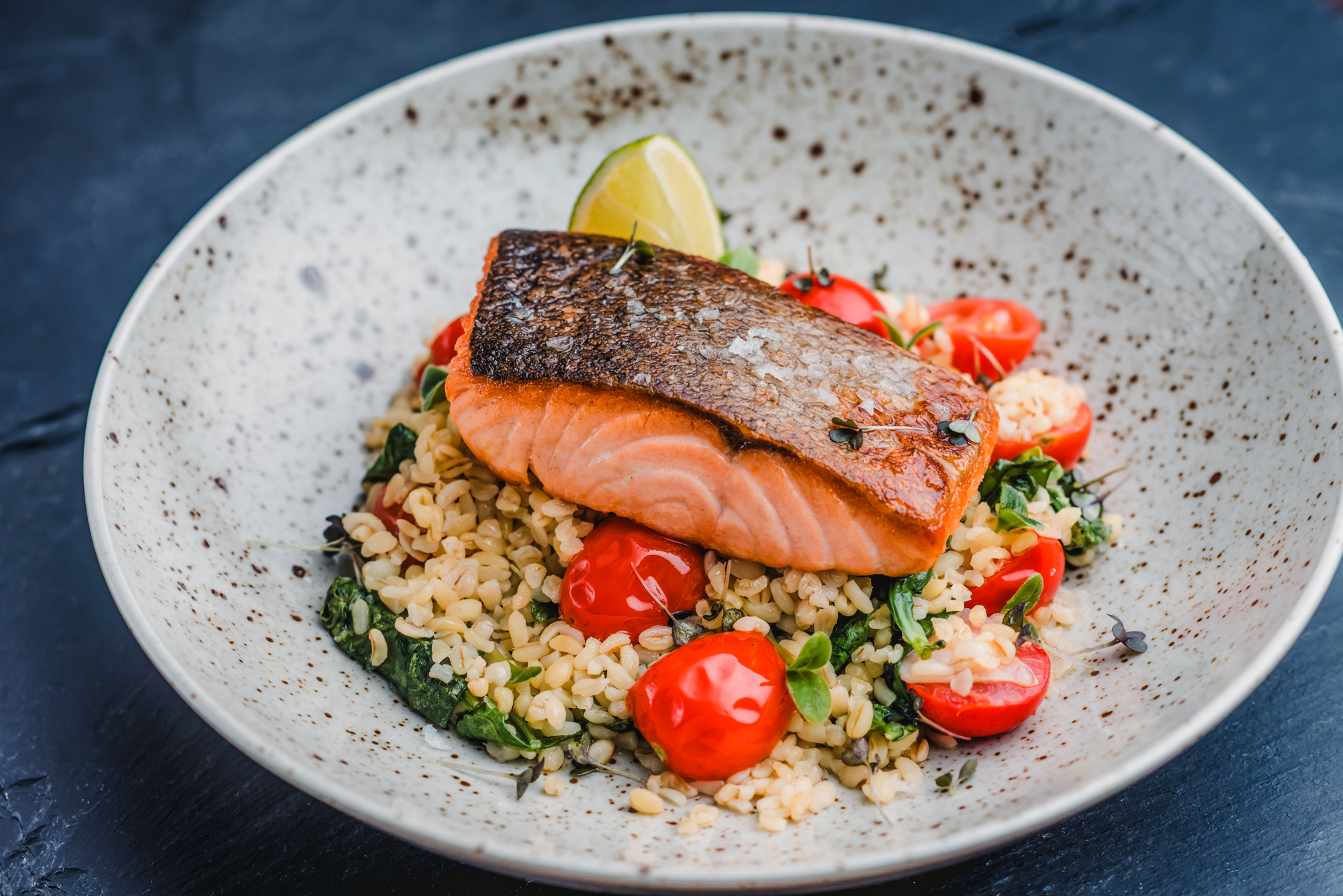 Close-up of grilled salmon on bulgur wheat salad with roasted tomatoes and fresh herbs at Rubin Hotel Budapest.