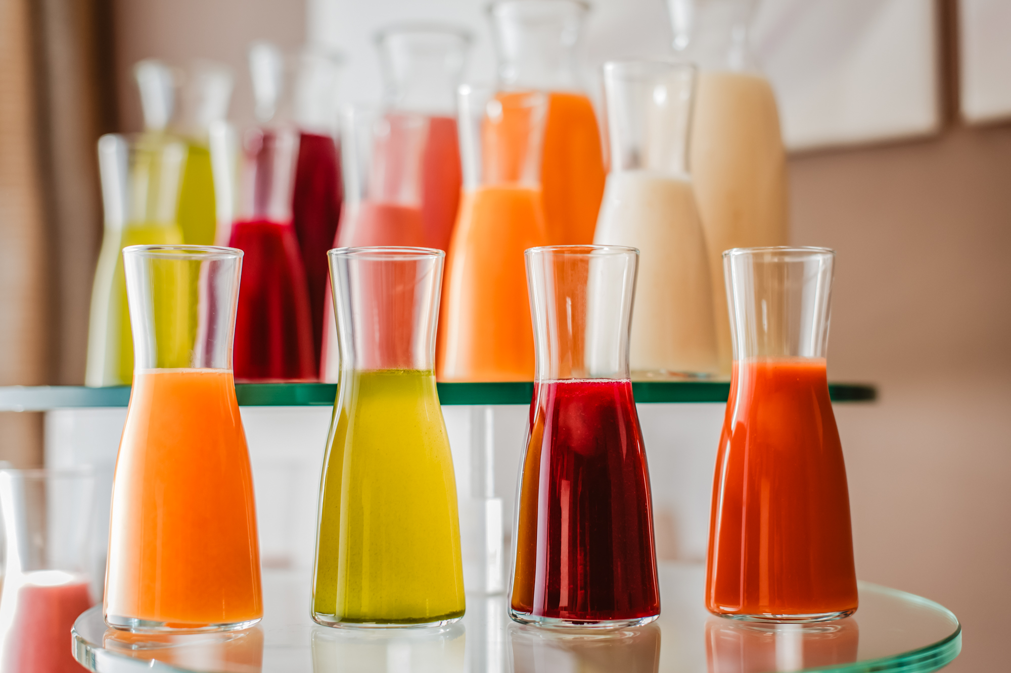 Glass carafes filled with colourful fruit juices displayed on a modern hotel catering drinks station.
