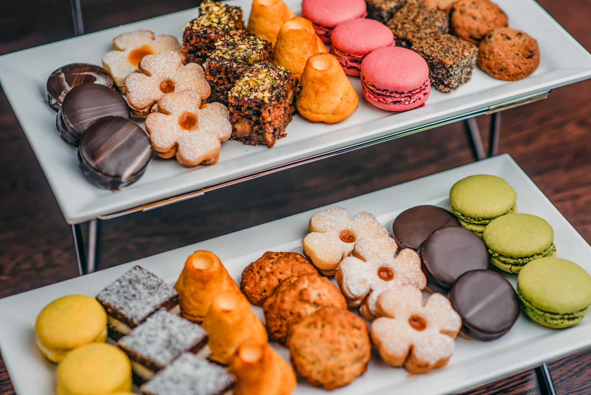 Colourful dessert selection with macarons, cookies, cakes, and pastries arranged on serving trays.