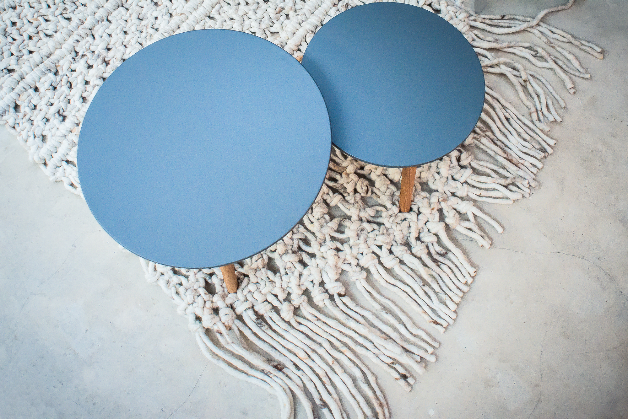 Round blue nesting tables placed on a handmade wool rug with tassel fringe.